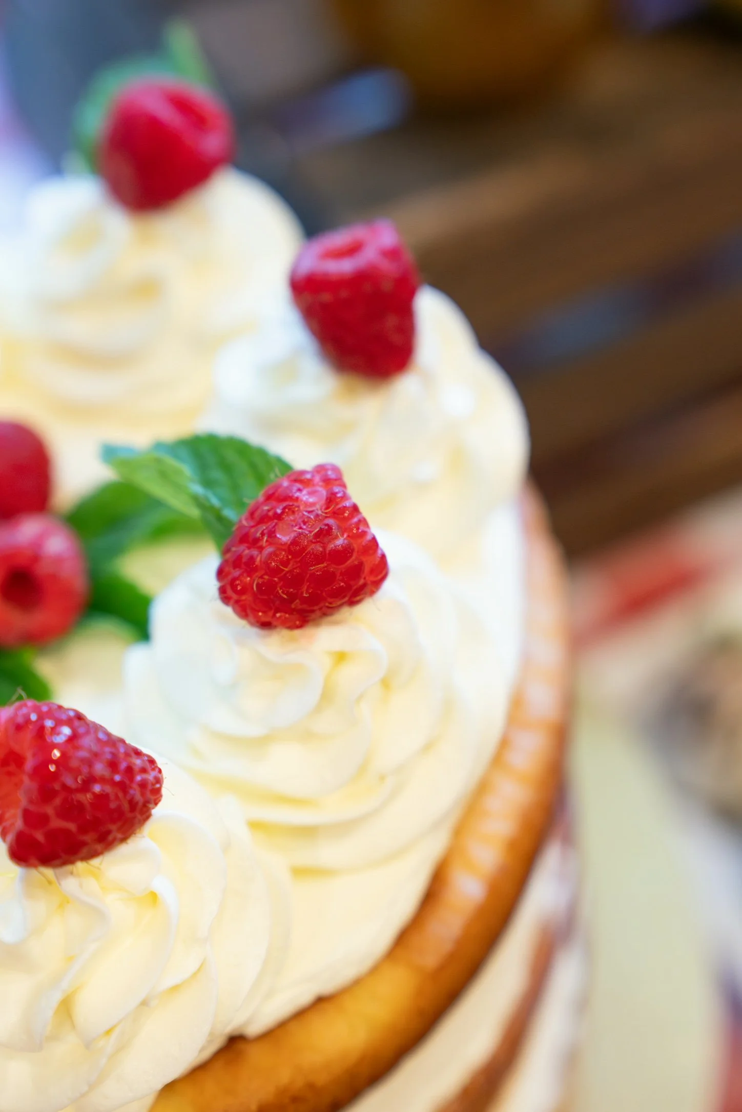 Close-up of a dessert with whipped cream, fresh raspberries, and mint leaves on a tart crust.