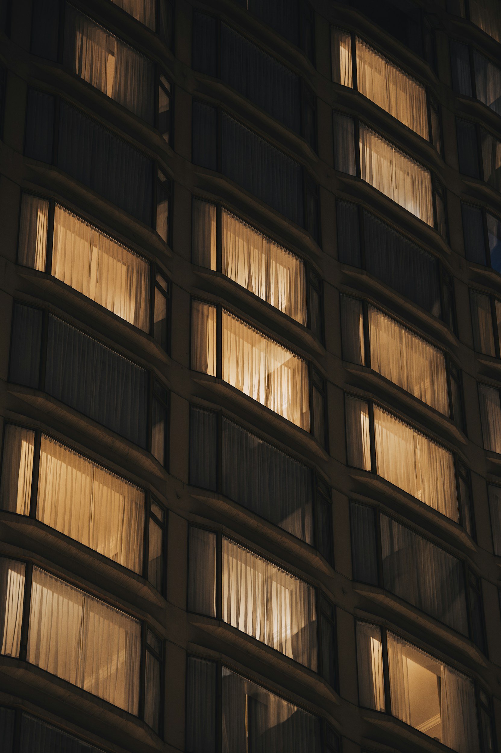 Warmly lit guest room windows on a hotel facade at night, hotel performance review