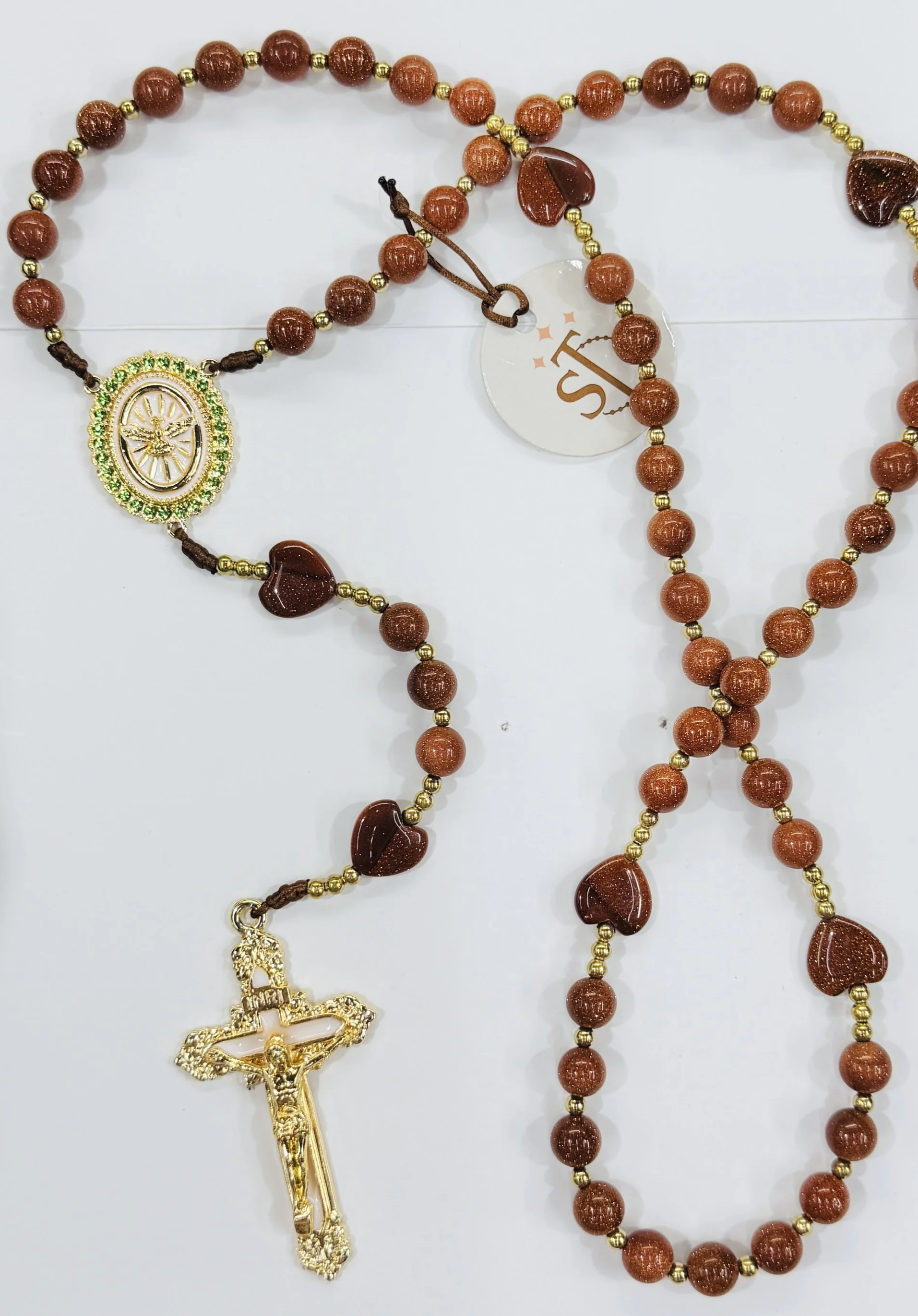 A string of brown wooden and gold beads with a gold crucifix pendant and a religious medallion, possibly a rosary, displayed against a white background.