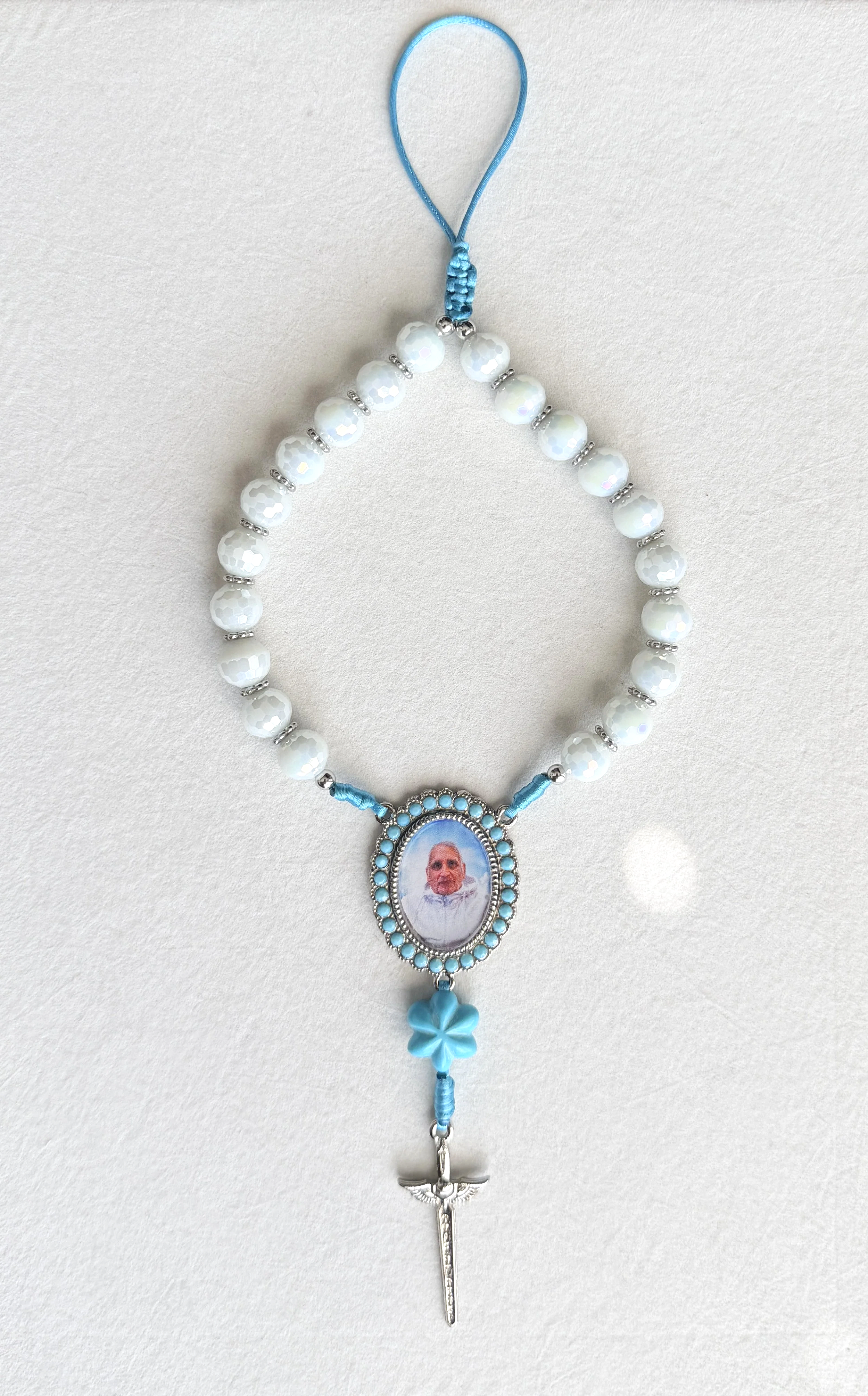 Blue and white beaded rosary with a picture of an elderly man in the center and a silver cross at the bottom.