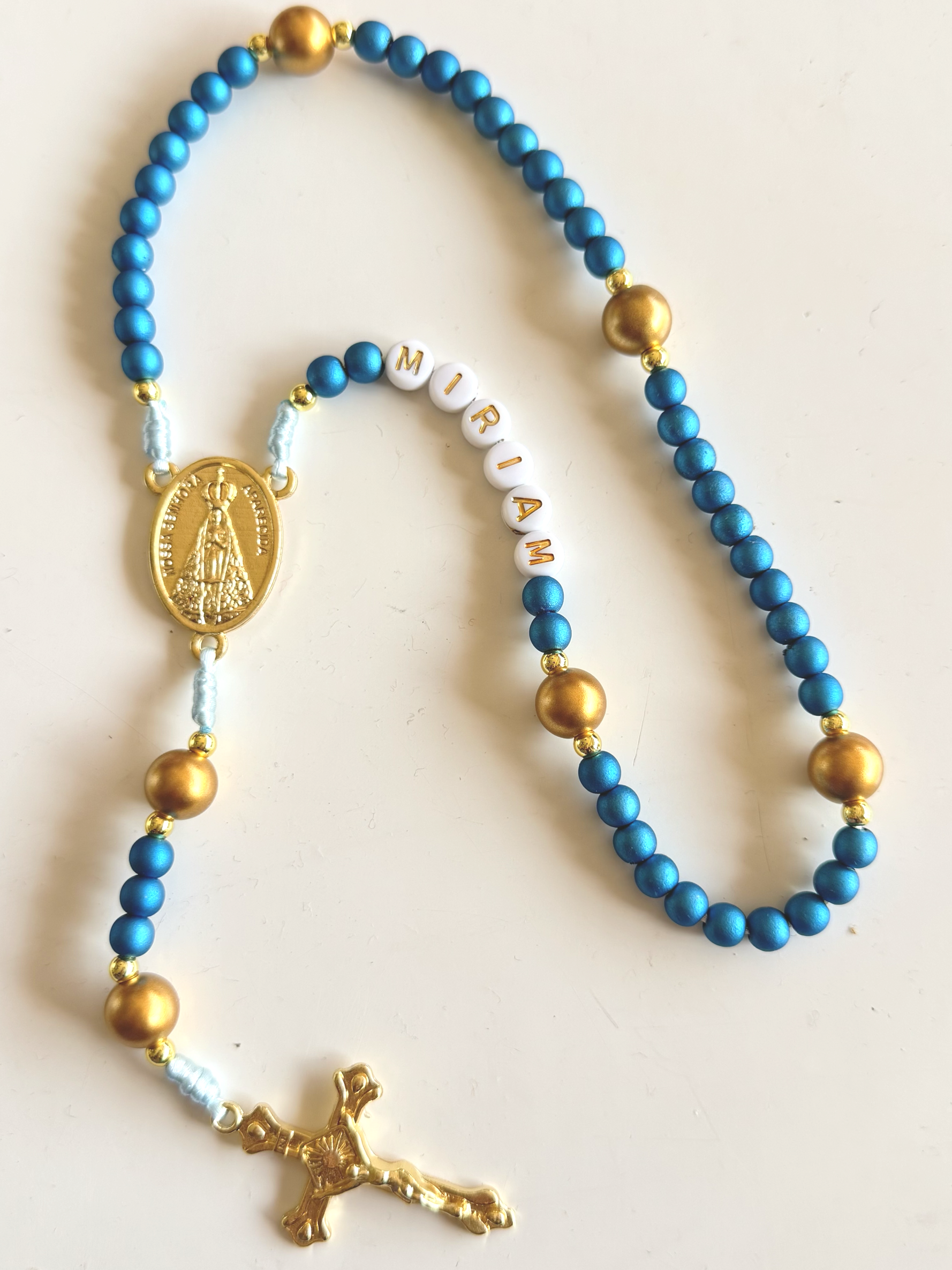 Blue and gold beaded rosary with a gold Jesus figure and a gold dog charm.
