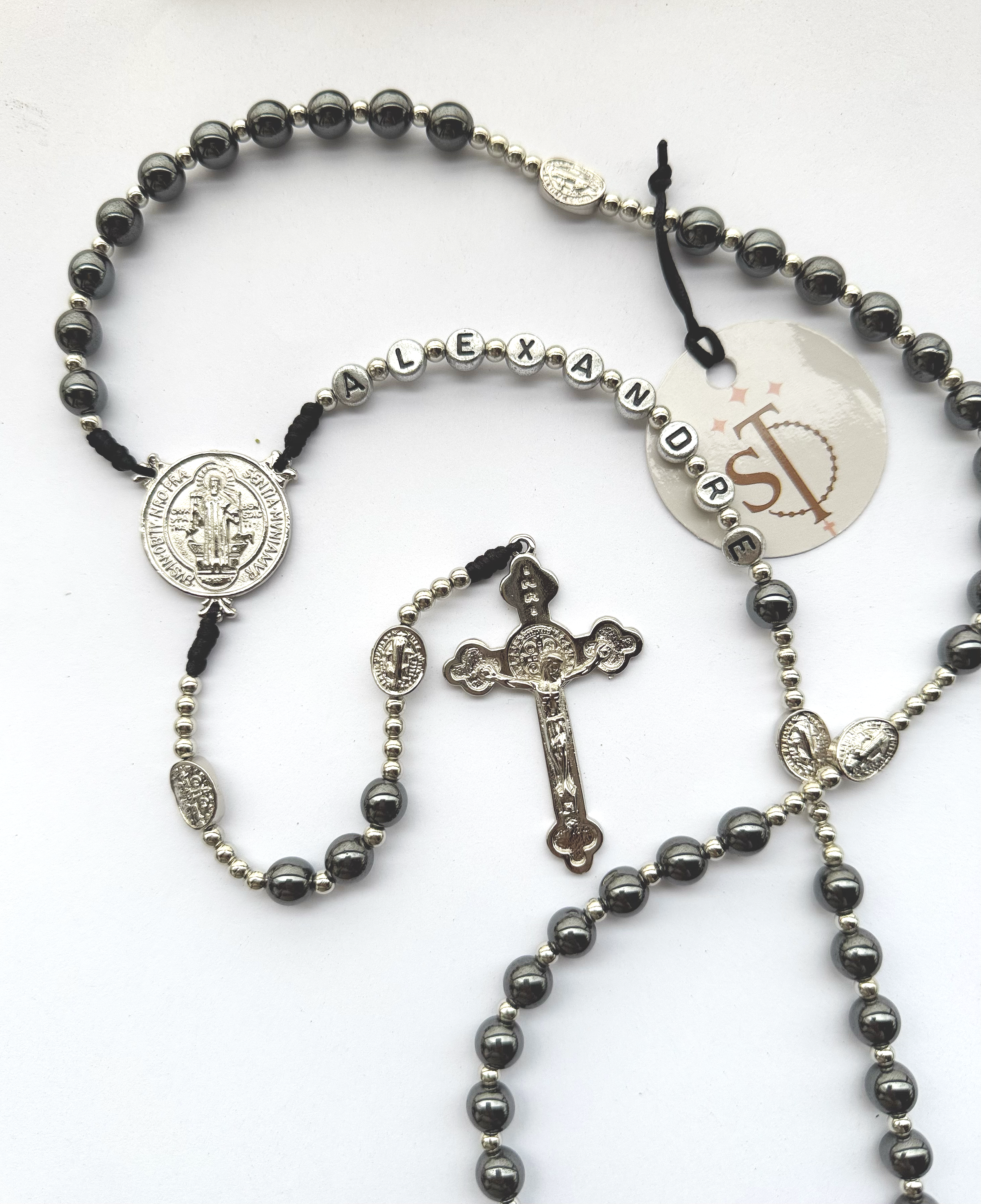 A set of black and silver beaded rosary necklaces with religious medals and crucifixes, arranged on a white surface.