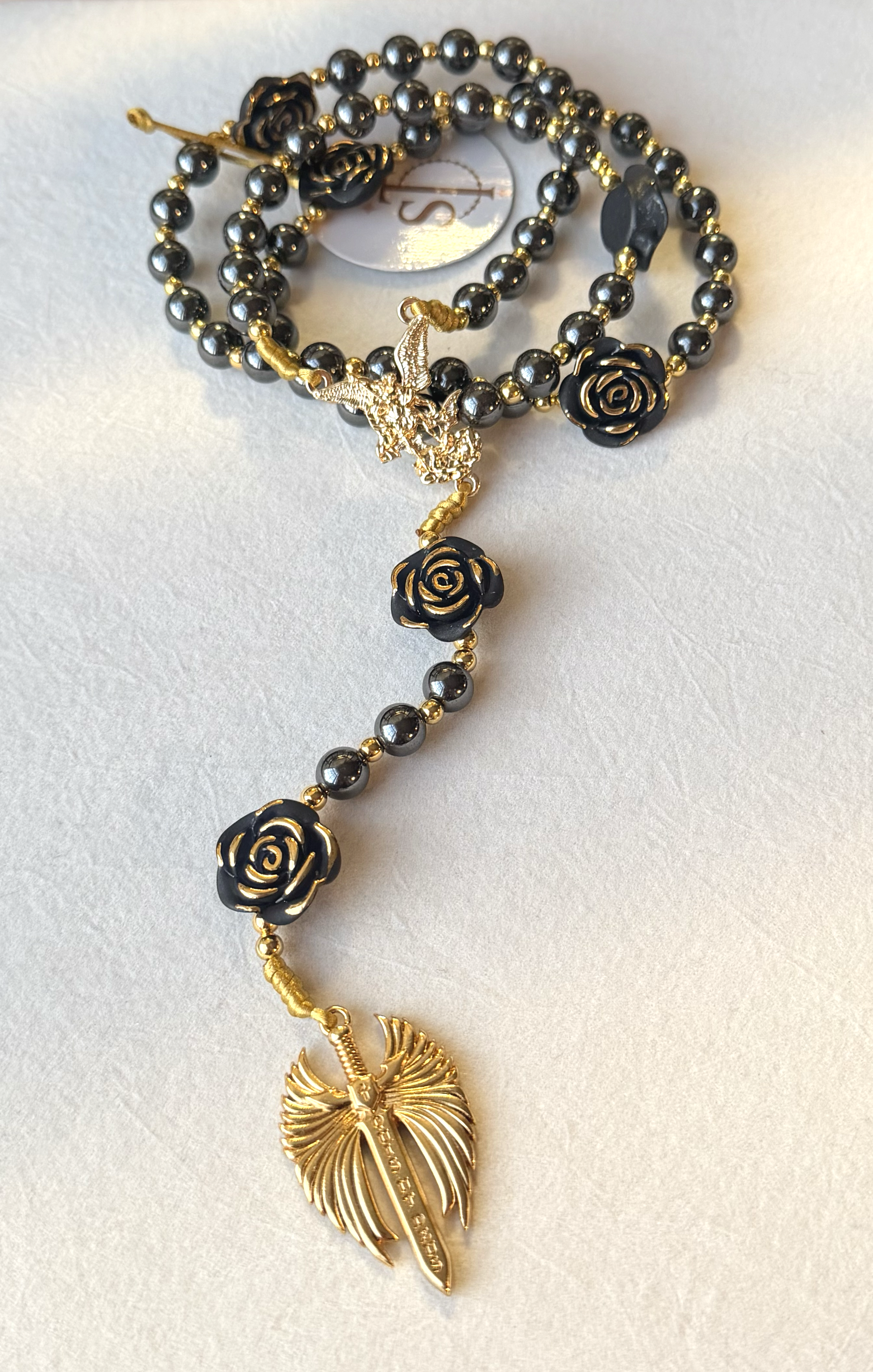 Black and gold beaded necklace with rose-shaped charms and a gold feather pendant.