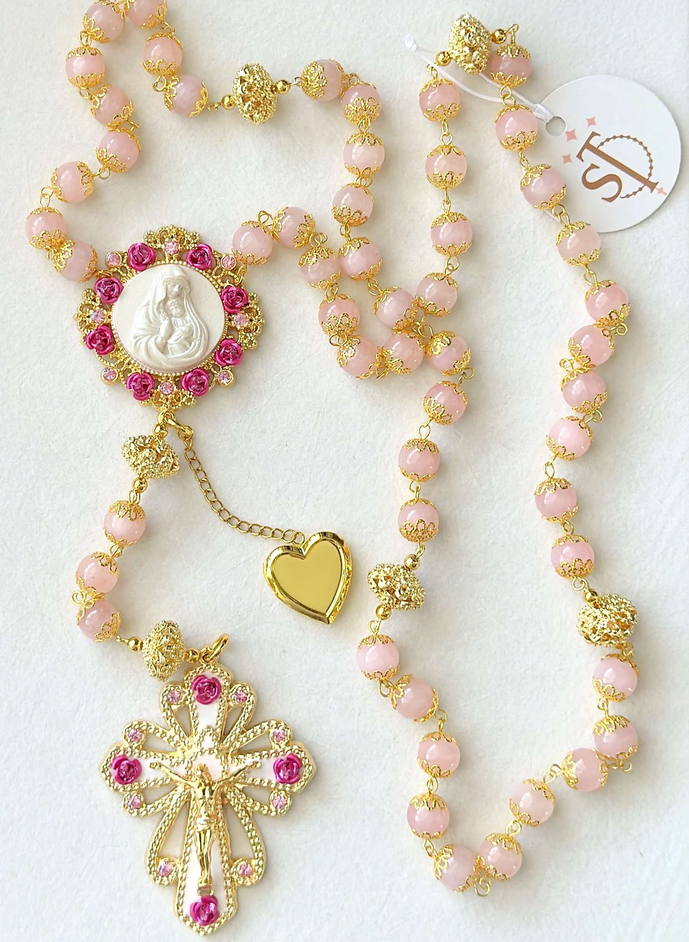 Gold and pink beaded rosary with a religious statue pendant and a gold bow charm.