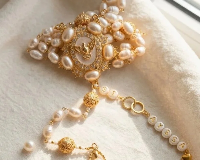 Gold and pearl jewelry with a watch face, pearl beads, and a personalized charm with the name 'Dayssa' on it.