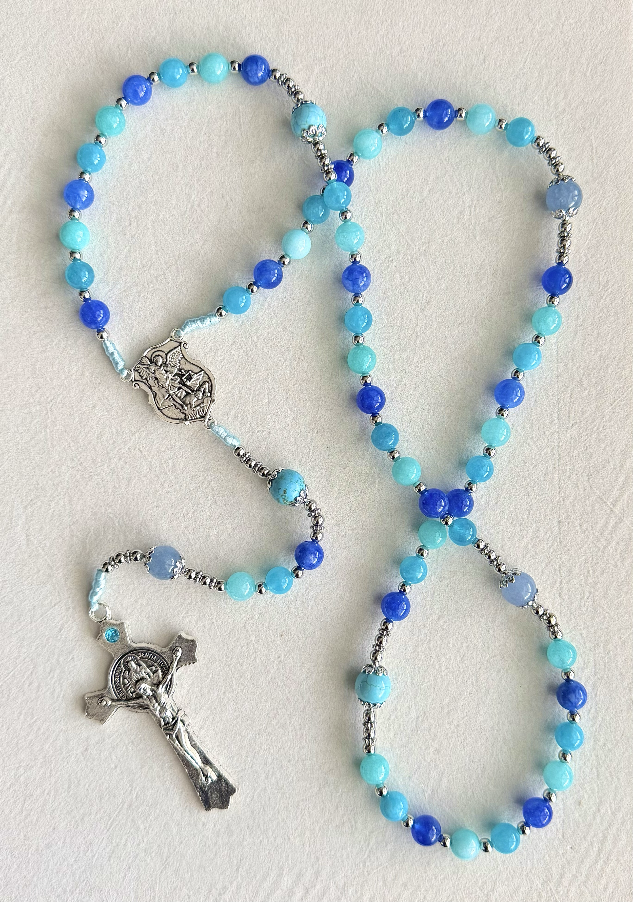 Beaded rosary with blue and turquoise beads and metal crucifix and religious medal.