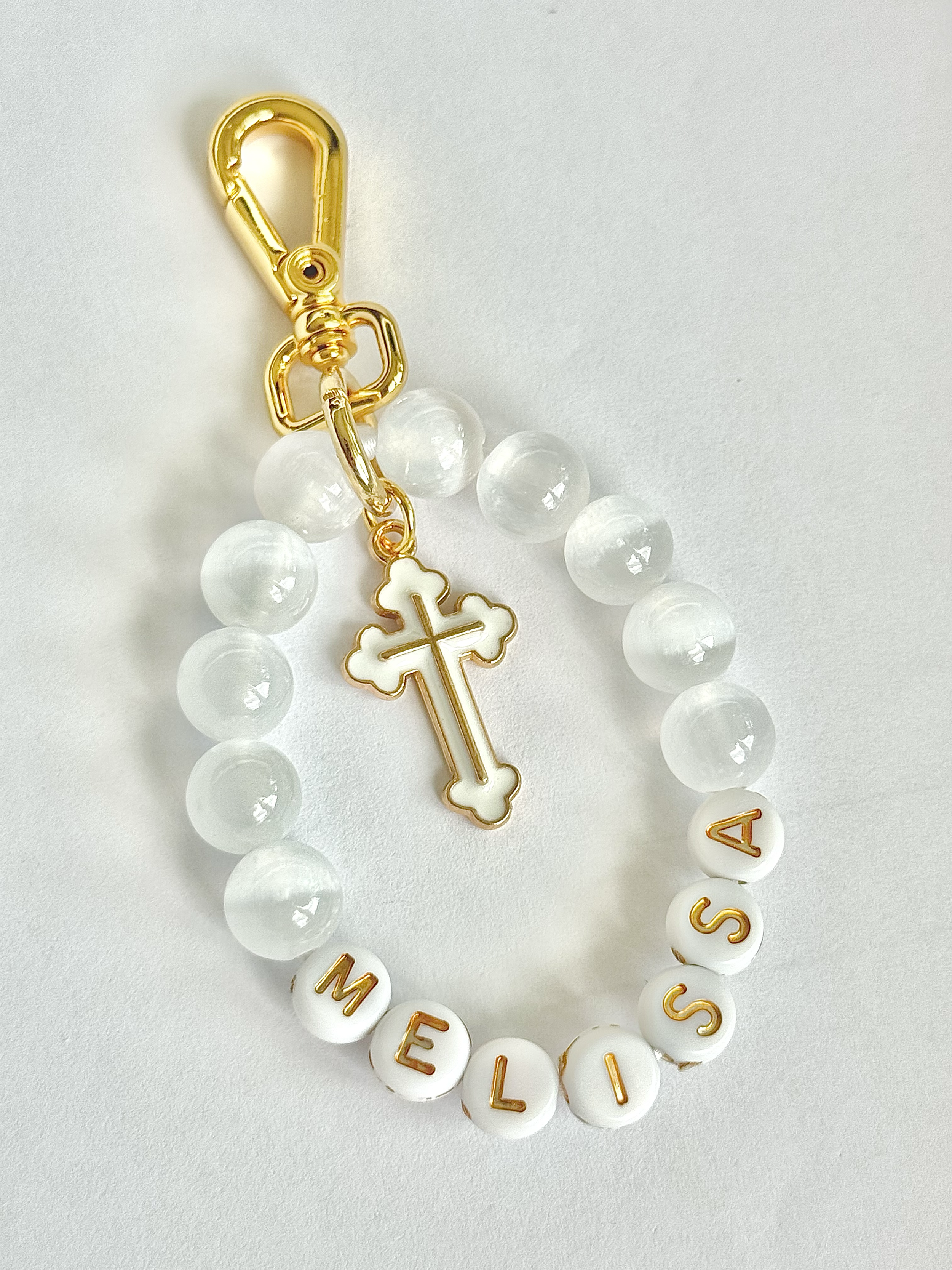 Bead necklace with gold-colored safety clasp and white round beads, spelling out 'WELCOME SISTERS' with gold lettering on white beads, against a white background.