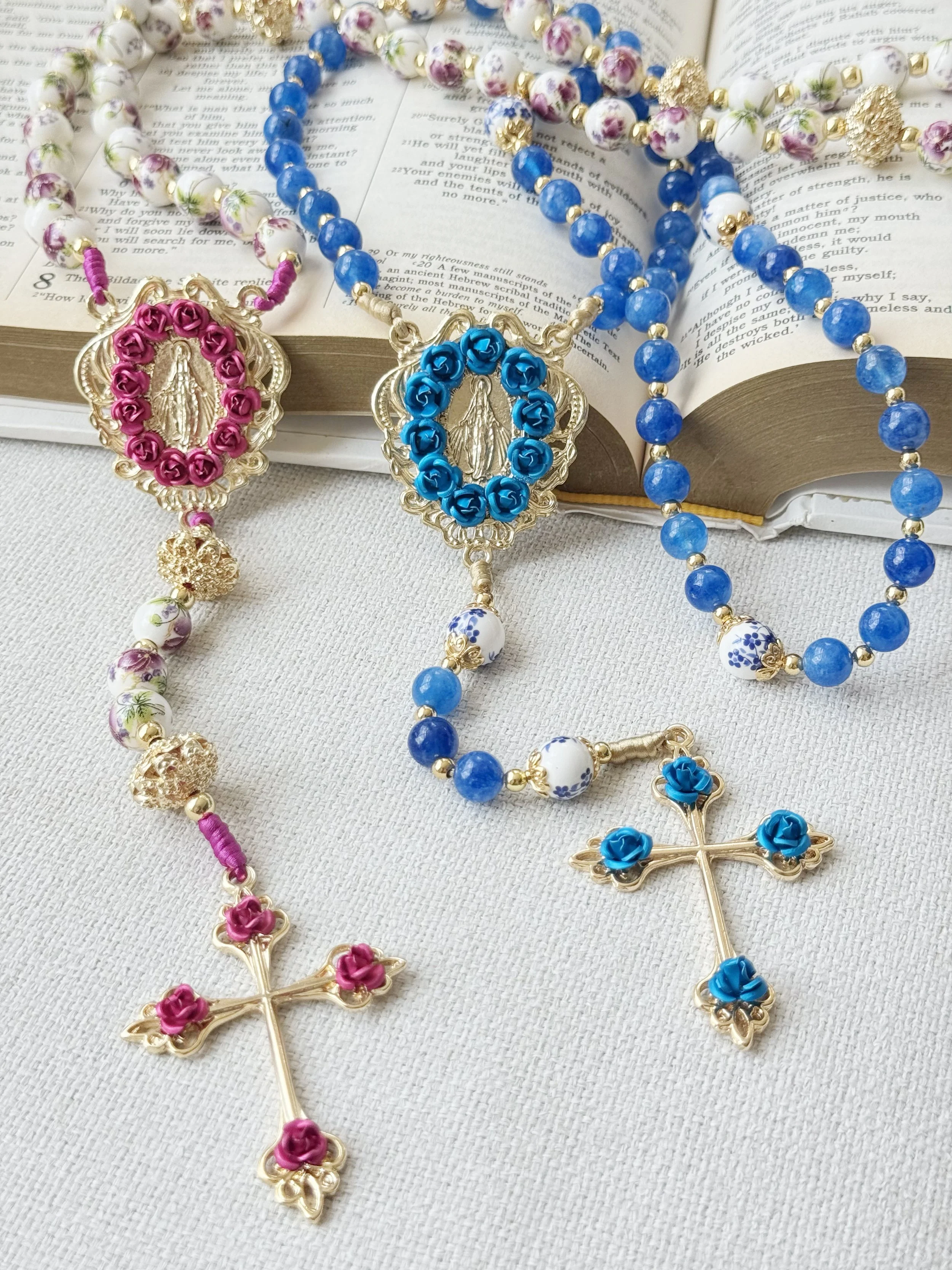 Close-up of religious jewelry including rosary beads and crucifixes, placed on an open book with text.