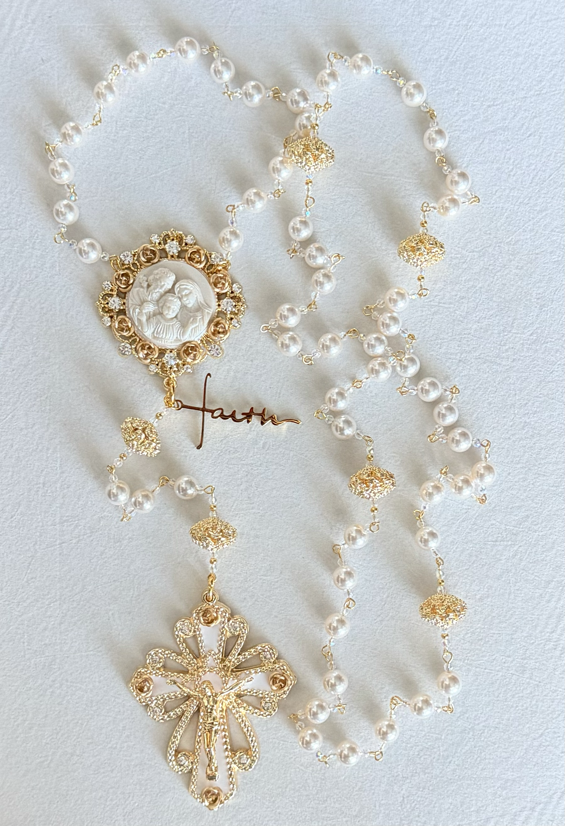 Gold and pearl rosary necklaces with religious and decorative medals, including a crucifix and a medal depicting the Holy Family.