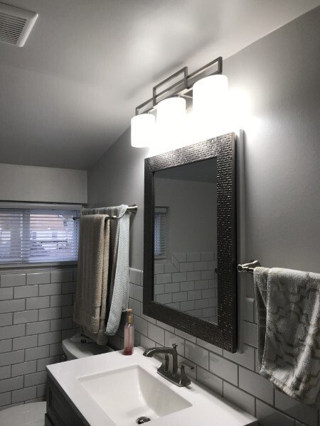 Bathroom with a sink, mirror, towel rack, and towels, illuminated by overhead lights.