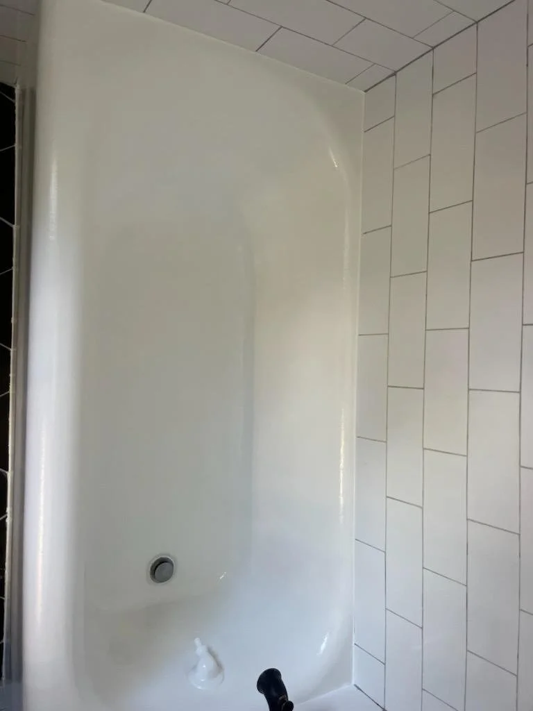 Empty white bathtub with drain and faucet in a tiled bathroom