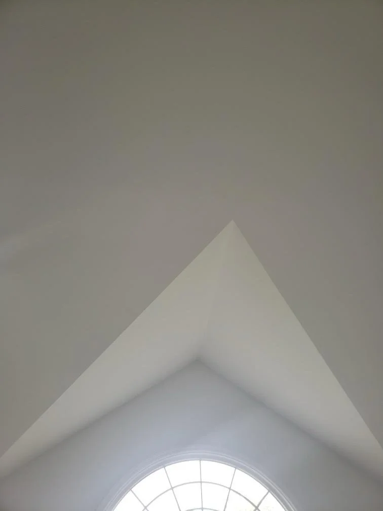 Interior view showing a vaulted ceiling with a gable end and a semi-circular window at the bottom.