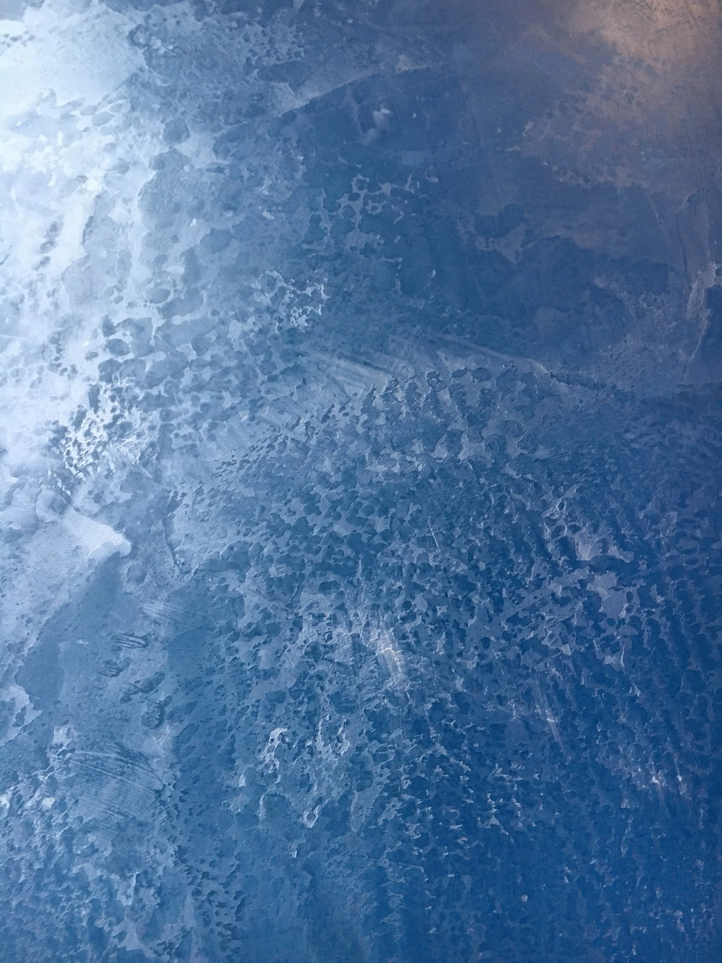 Close-up view of ice or frozen surface with textured patterns and various shades of blue.