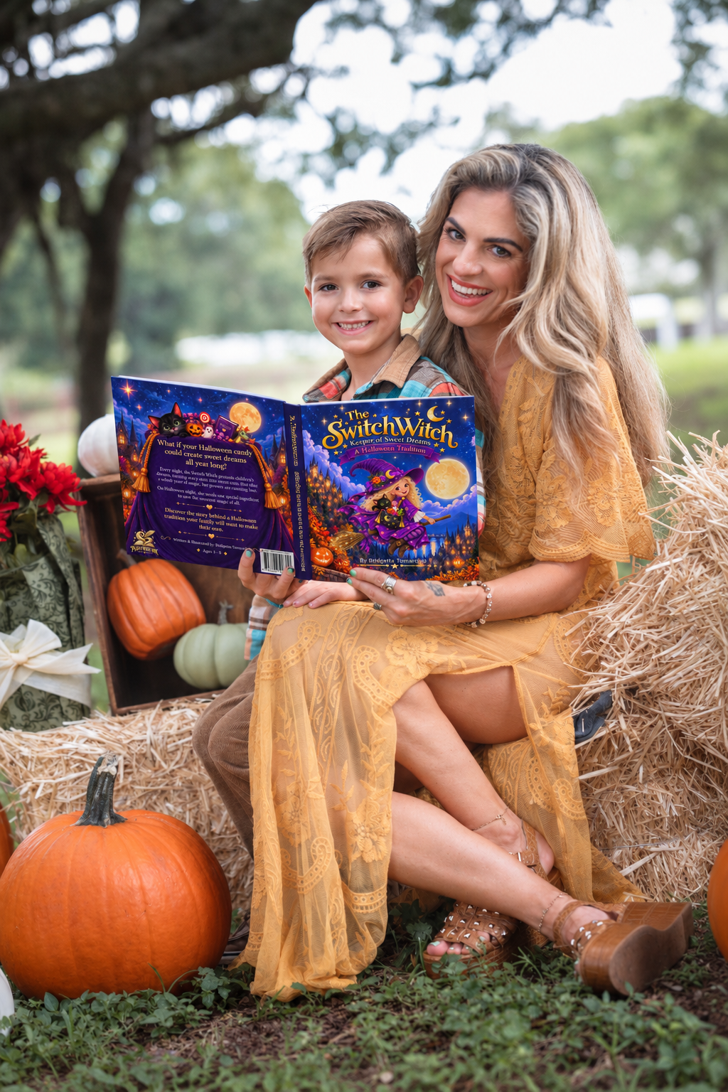 A woman and a boy sitting on hay bales outdoors, reading a colorful Halloween-themed book titled "The Switchwitch". The scene is decorated with pumpkins, gourds, and flowers, with trees and green grass in the background.