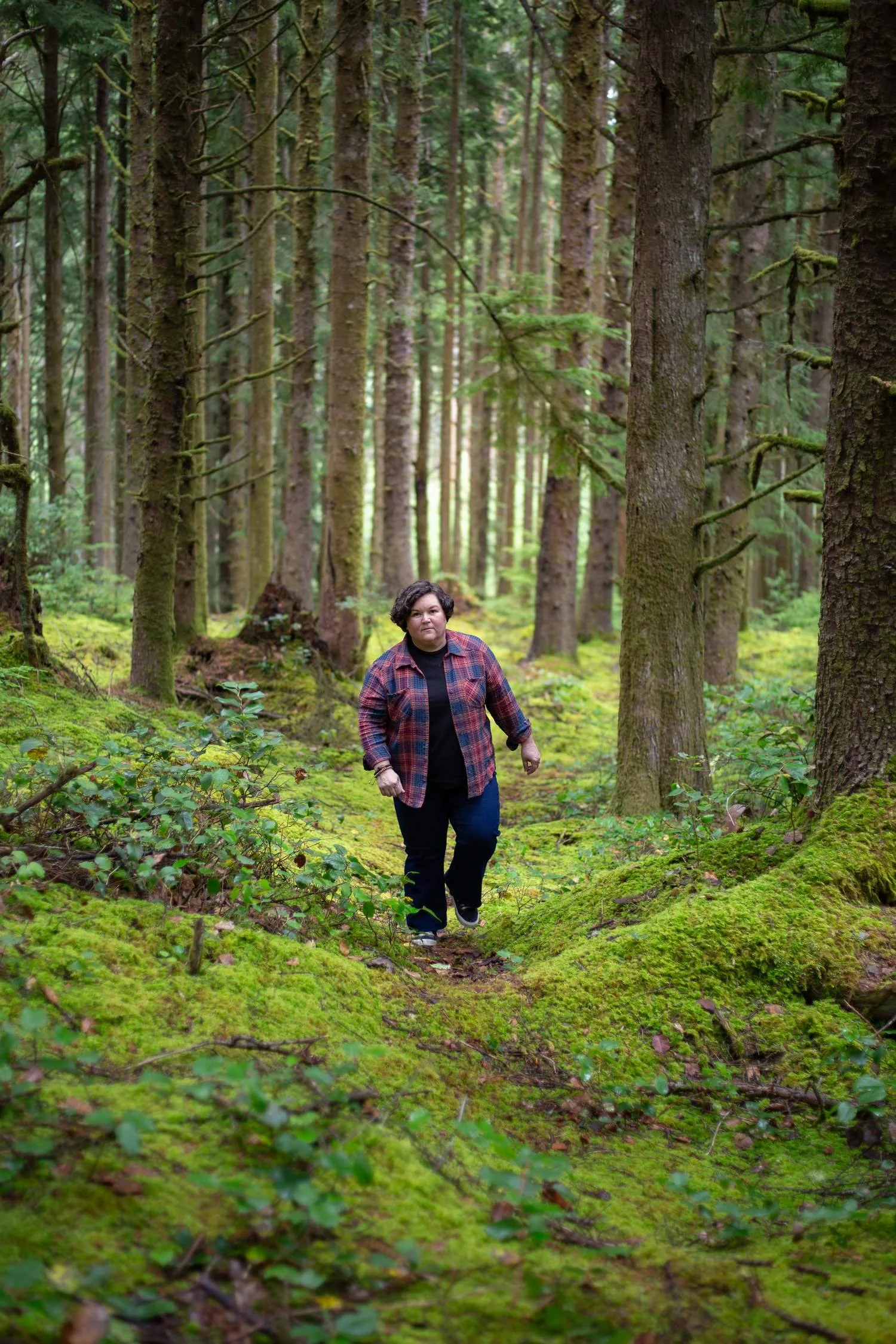 Person walking through a moss-covered evergreen forest
