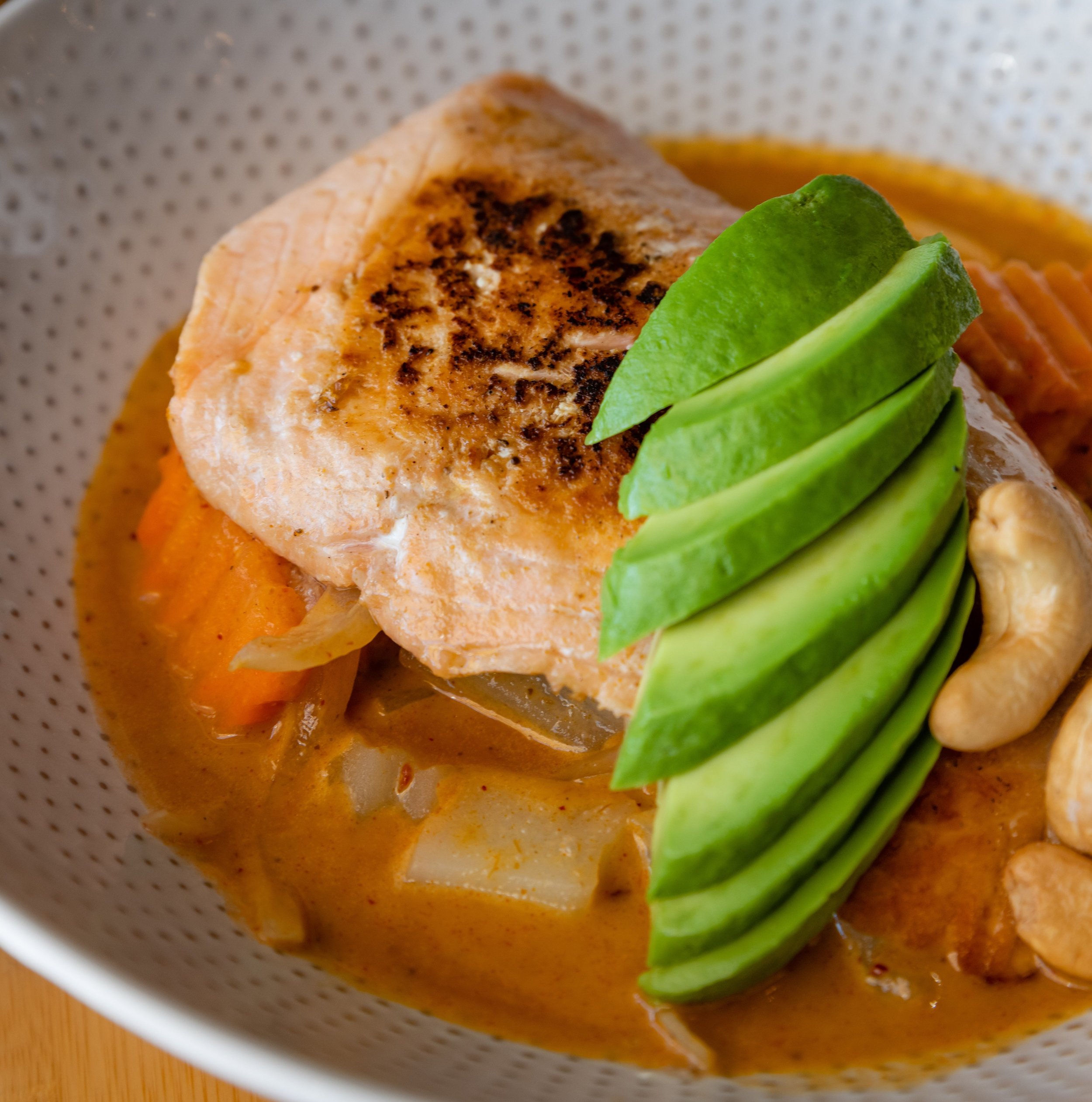 Salmon fillet with sauce and sesame seeds, served with mixed vegetables including broccoli, carrots, and baby corn.