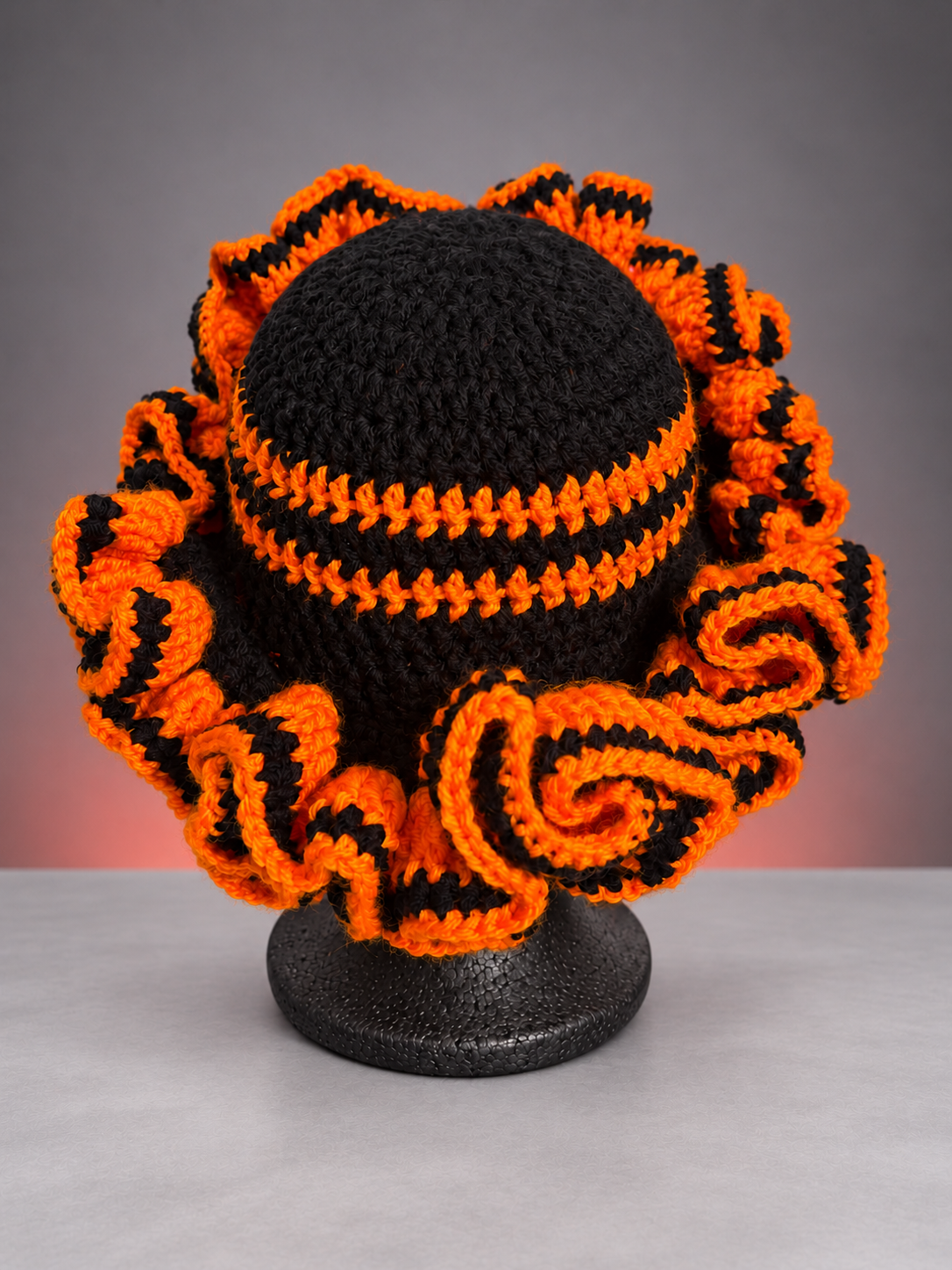 Orange-black ruffle hat in grey studio.png