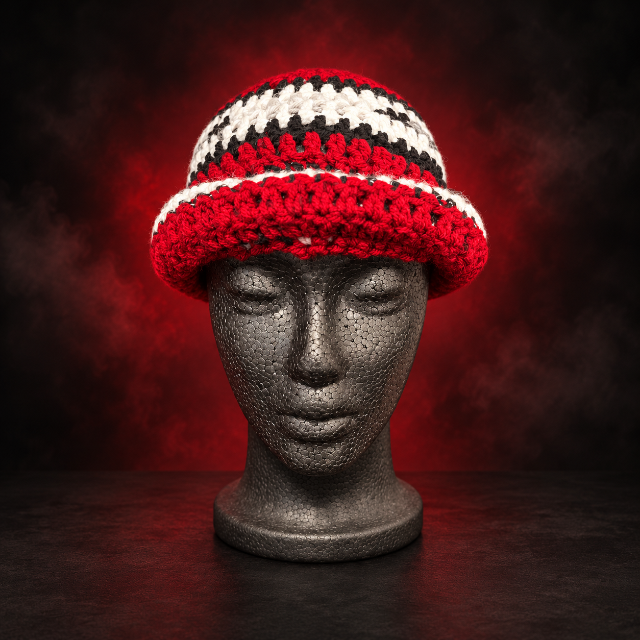 Handmade red, black, white and gray crochet beanie shown folded up. Unfold it to wear it as a ski mask—the same piece with a different look. Crafted Different. Worn Bold.
