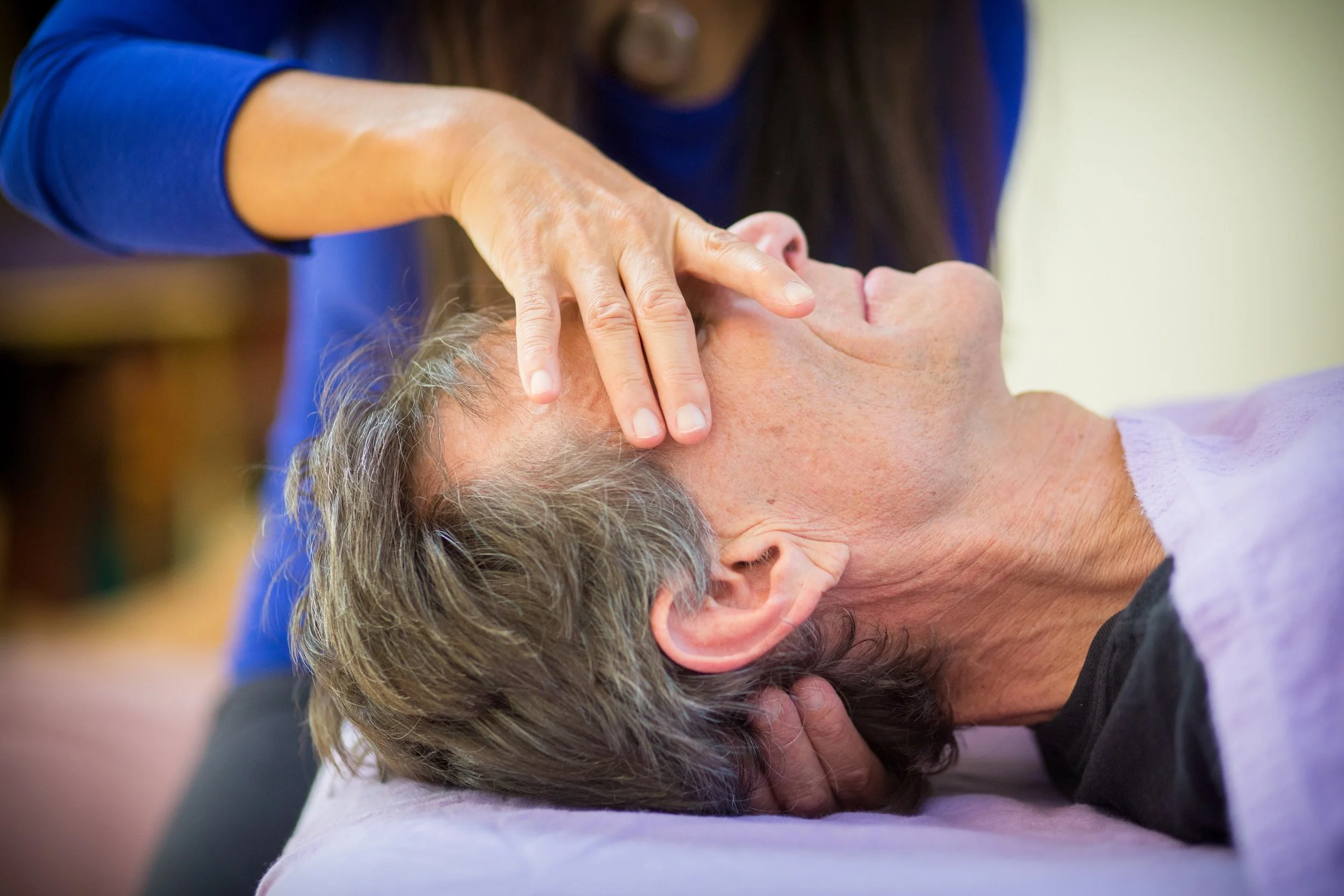 Yasue Tanaka providing gentle craniosacral therapy to a client resting on a treatment table in San Rafael, Marin County.