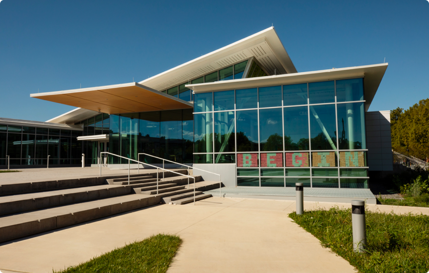 Siebel Center for Design with a sloped roof and stairs leading up to the entrance. The sign on the window spells out "BEGIN" in colorful letters.