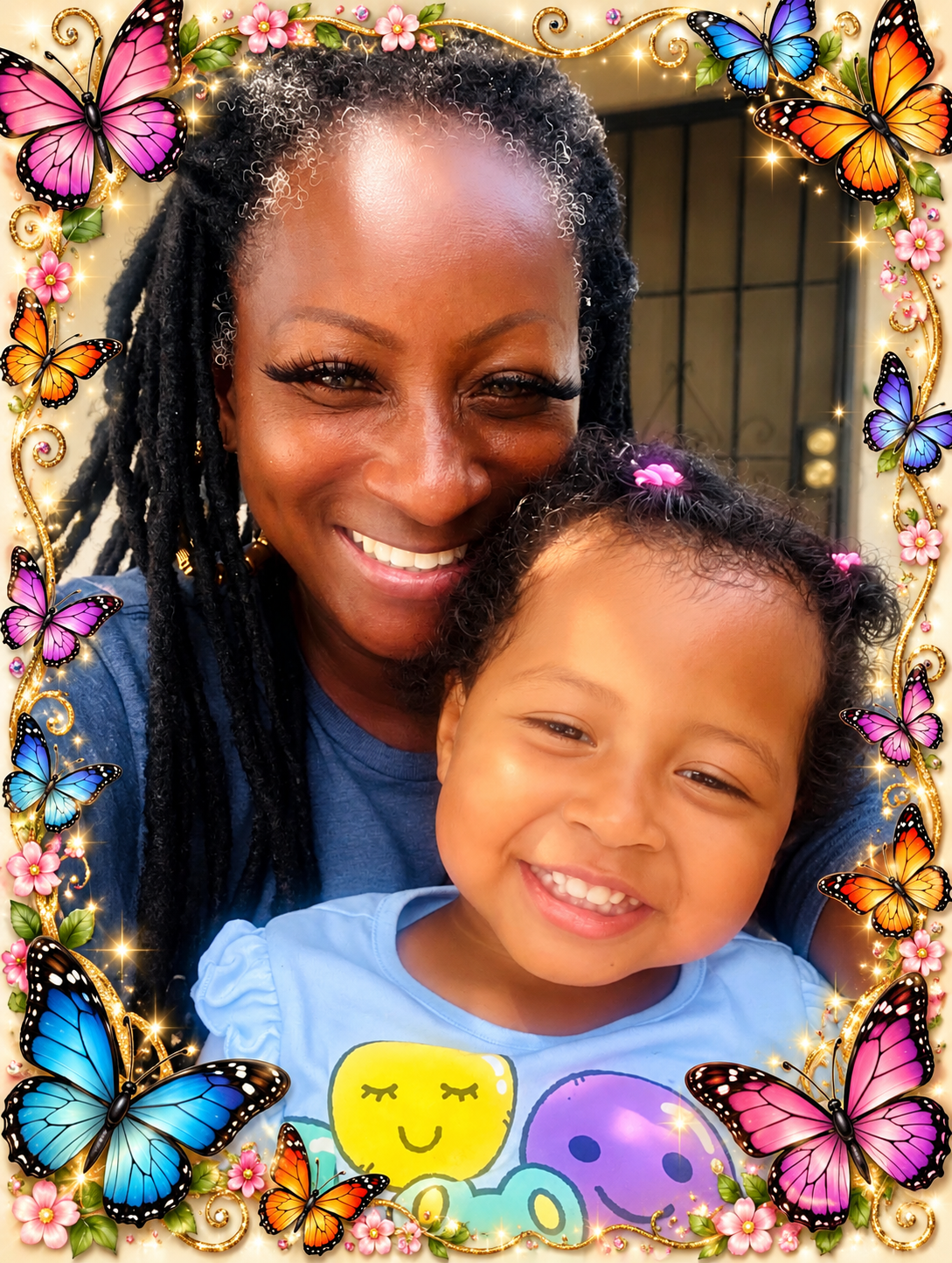 A smiling woman and a young girl smiling in close-up selfie, framed by colorful butterflies and pink flowers with a golden border.