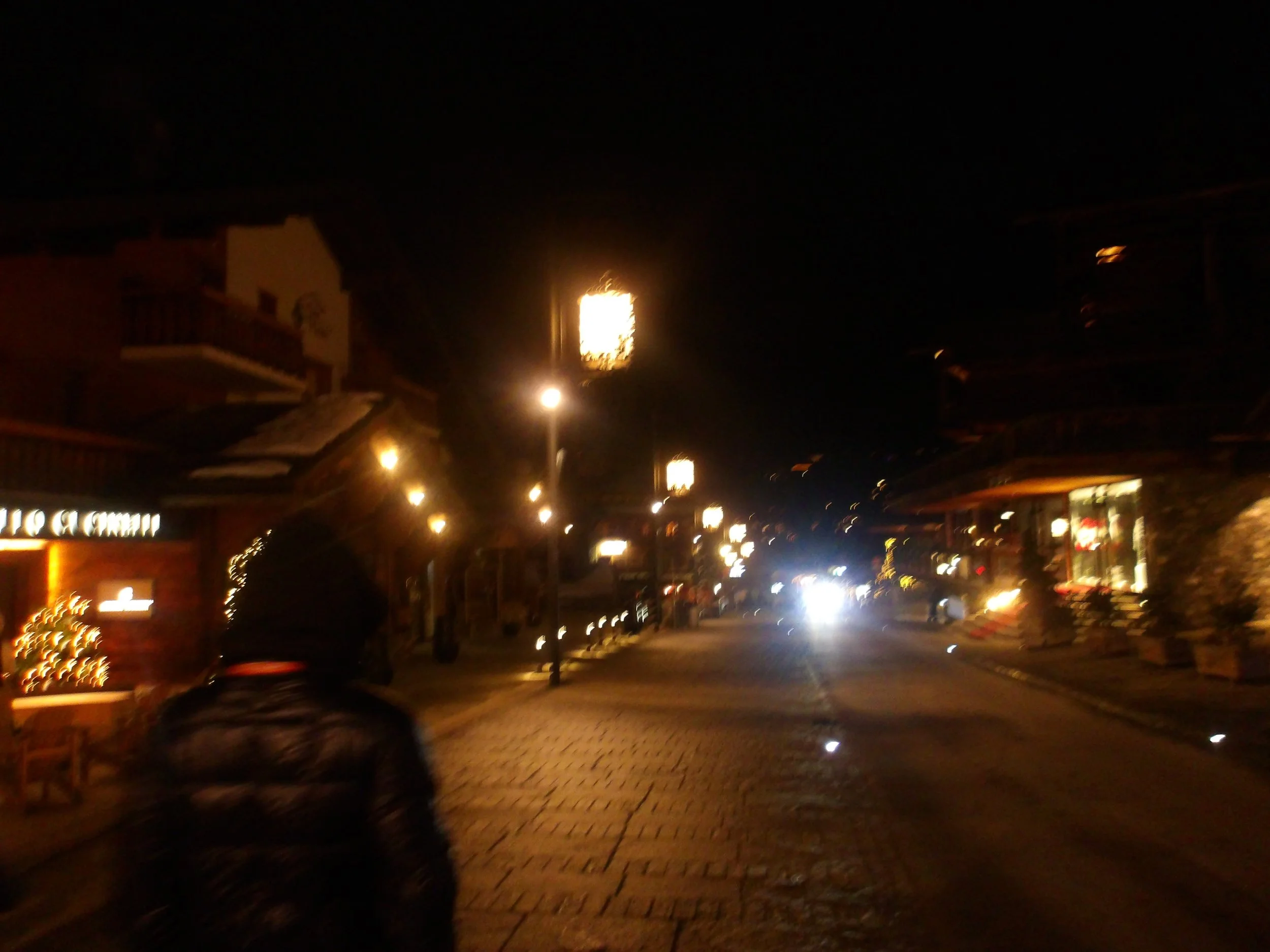 Nighttime street scene with illuminated signs, street lights, and buildings.