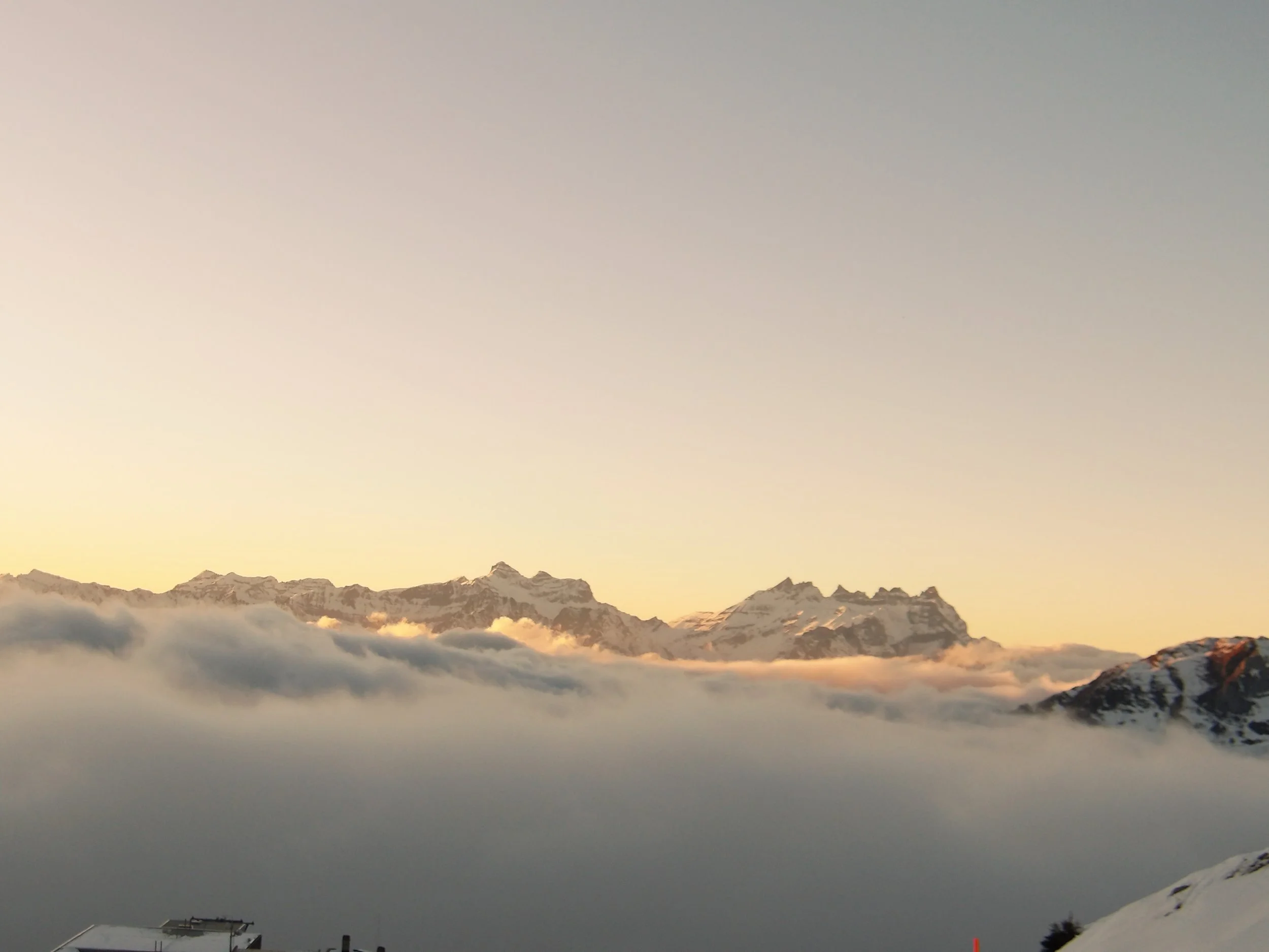 Snow-capped mountain range under a clear sky with some clouds.