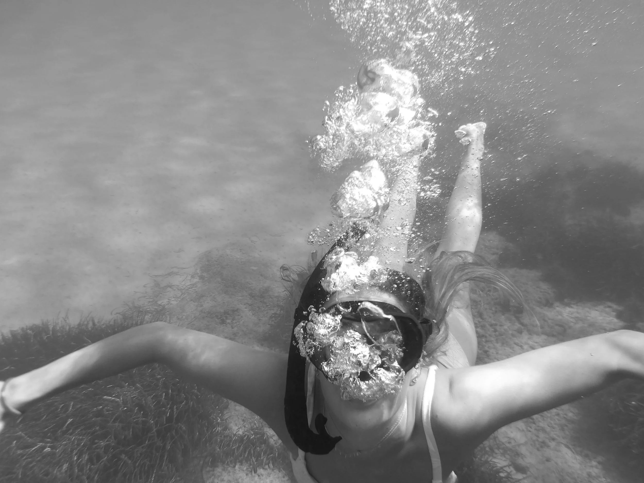 Person underwater in the ocean, with arms outstretched and water splashing around.