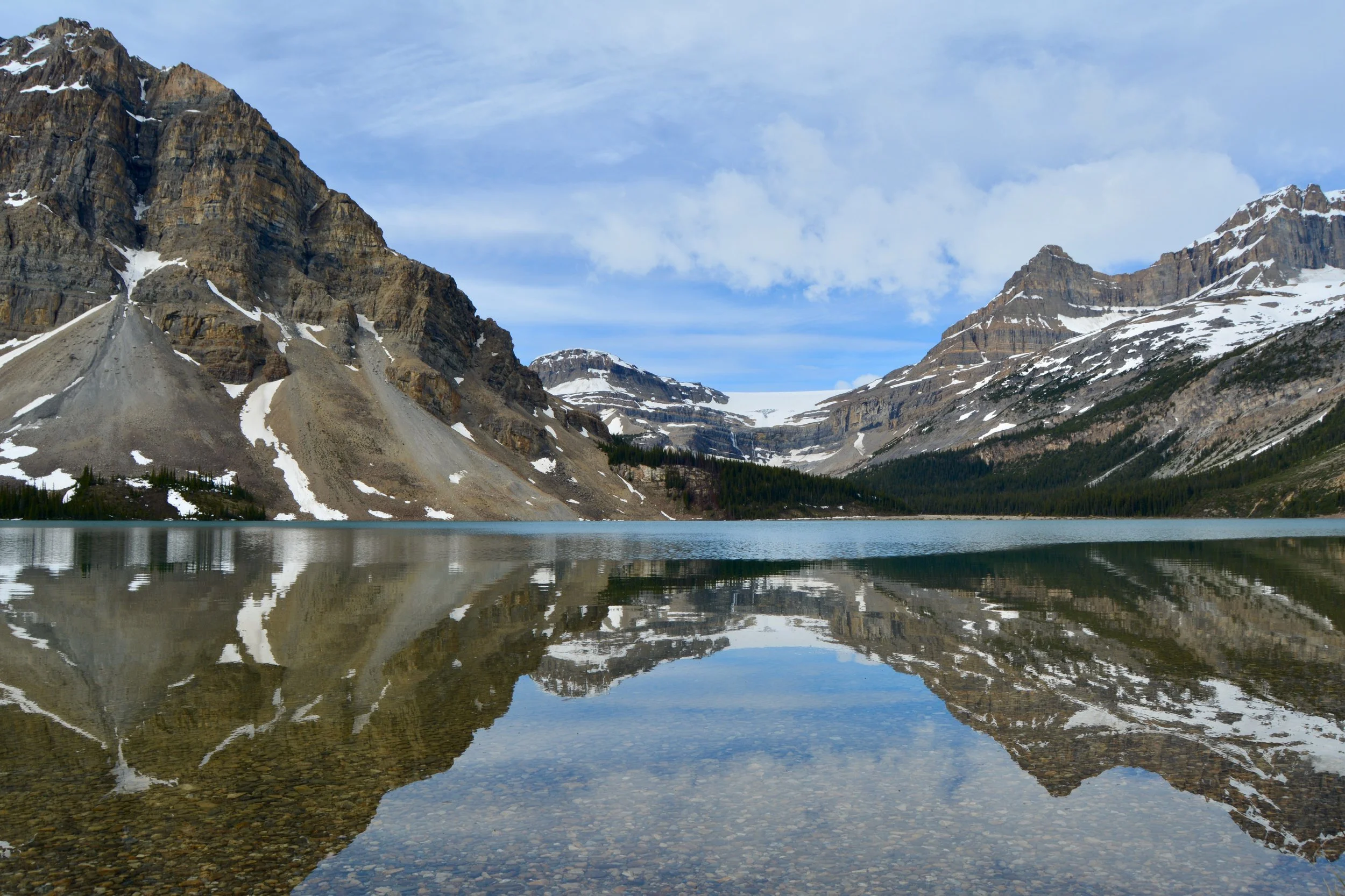 Mountains with snow patches reflected in a clear mountain lake