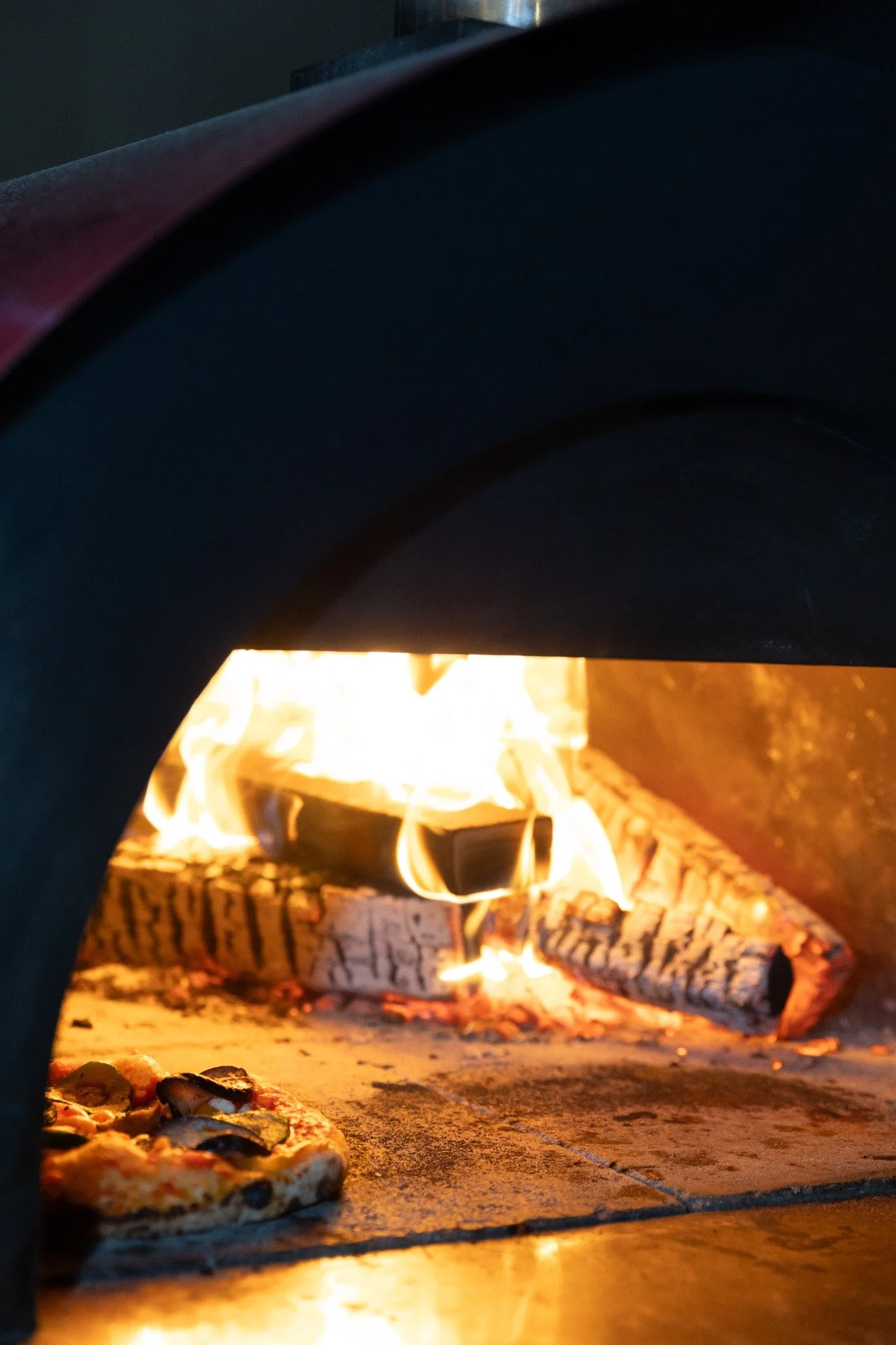 Pizza baking inside a wood-fired oven.