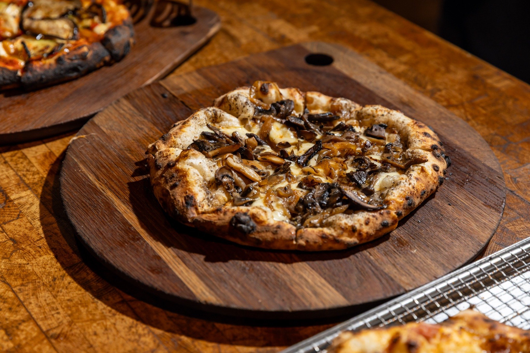 Mushroom pizza on a wooden serving board.