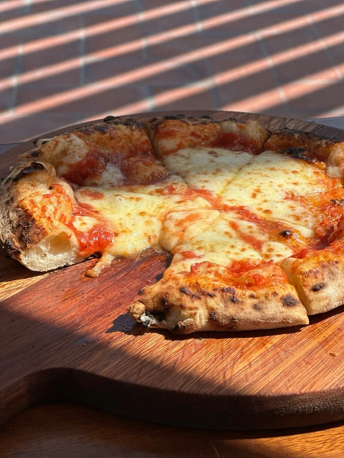 Freshly baked pizza with toppings on a wooden serving board.