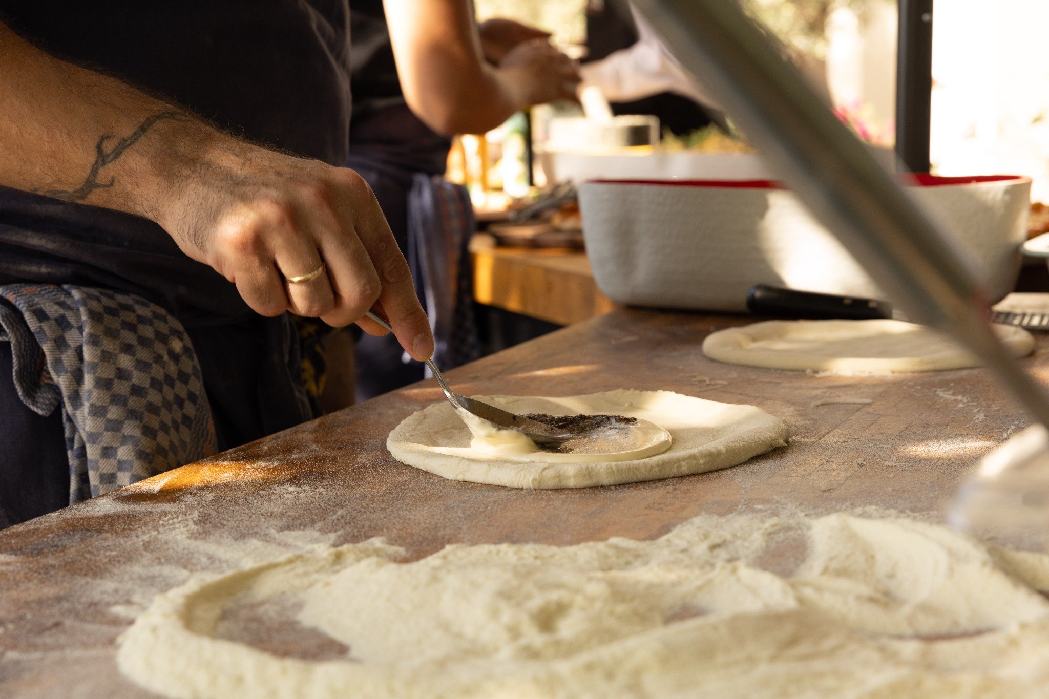 Spreading the base topping on stretched pizza dough.