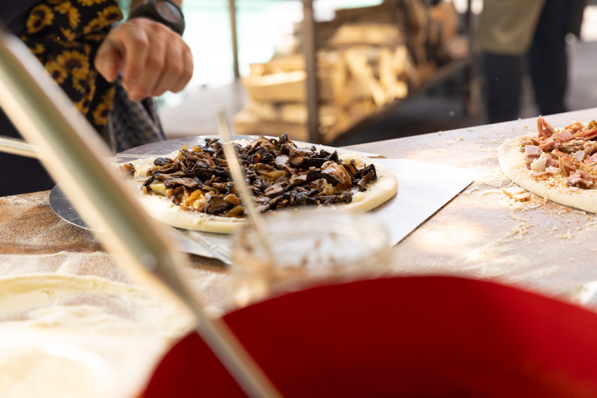 Adding mushroom toppings to freshly stretched pizza dough.