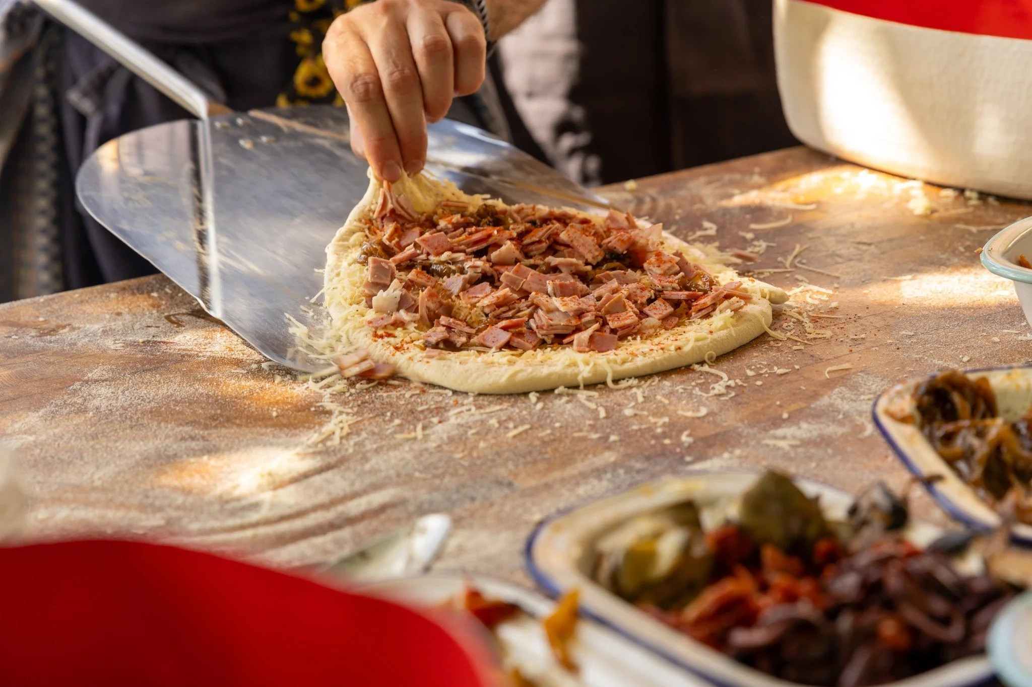 Adding toppings to a pizza before baking.