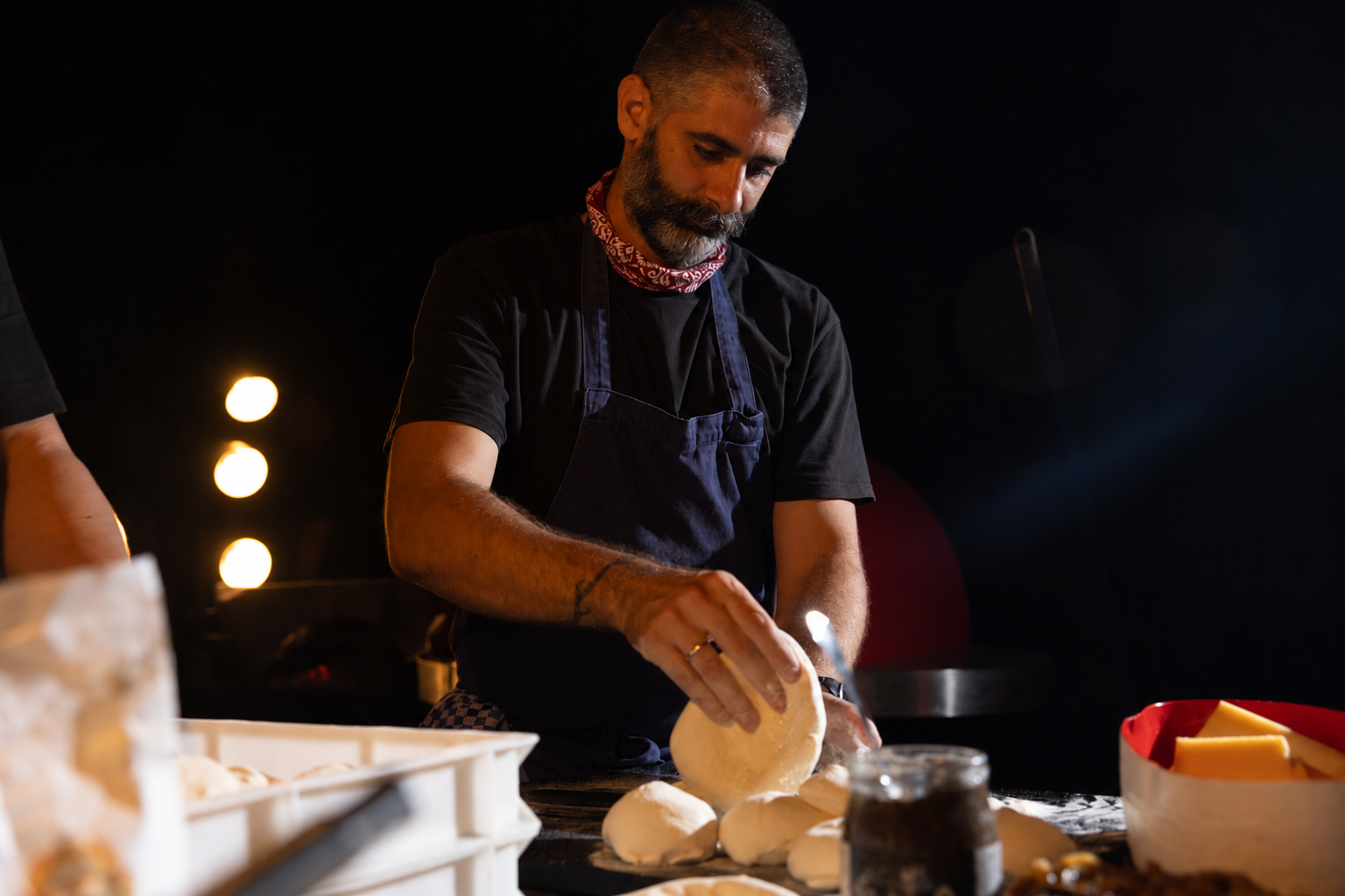 Bilal preparing sourdough pizza dough in a navy apron.