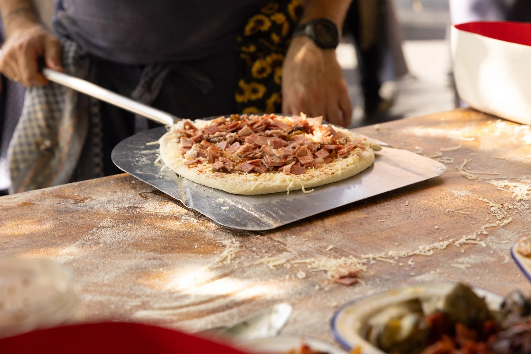 Preparing a topped pizza on the oven peel.