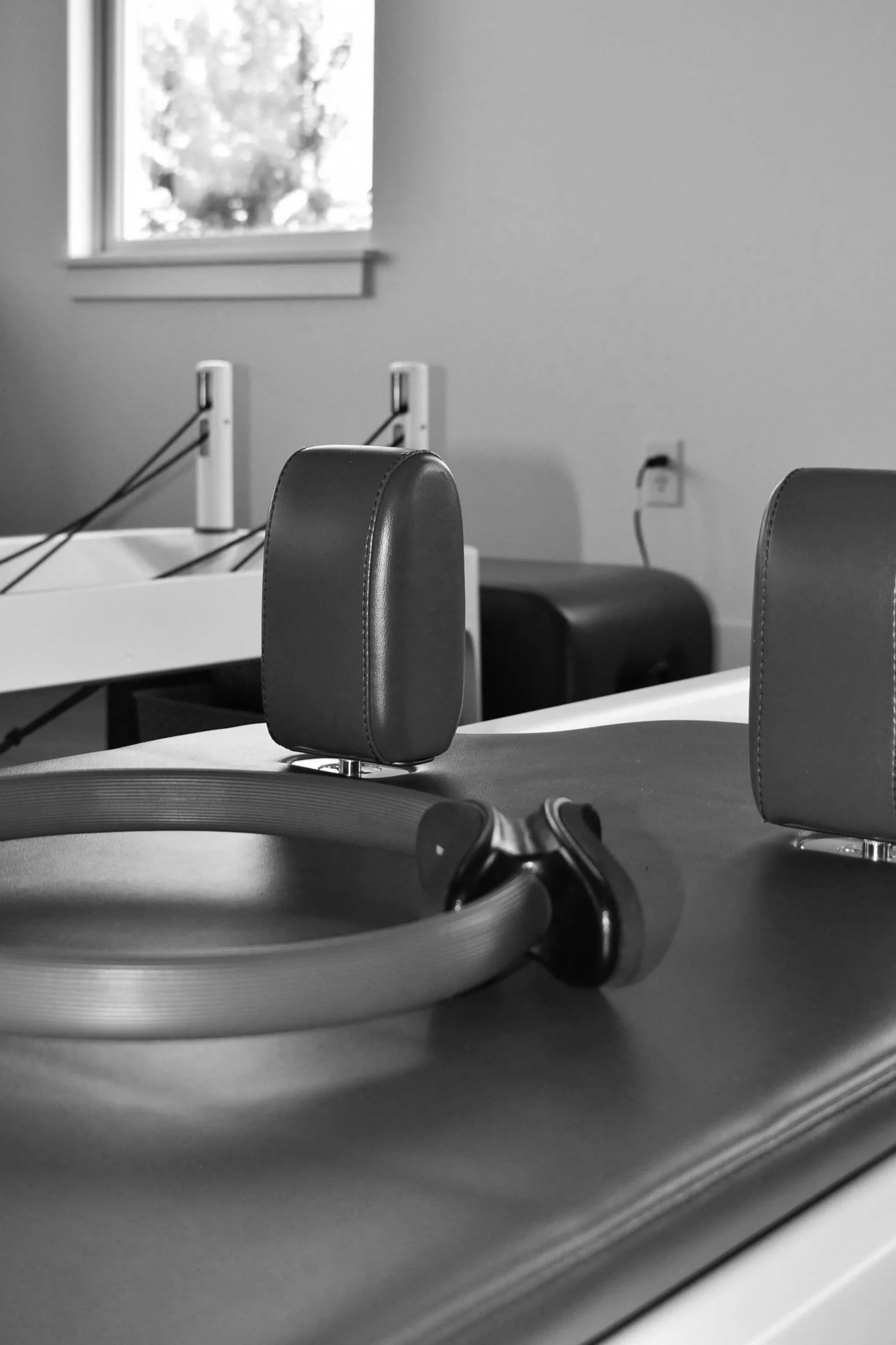A room with a window, a chair, and a treadmill or desk exercise equipment. The image is in black and white.