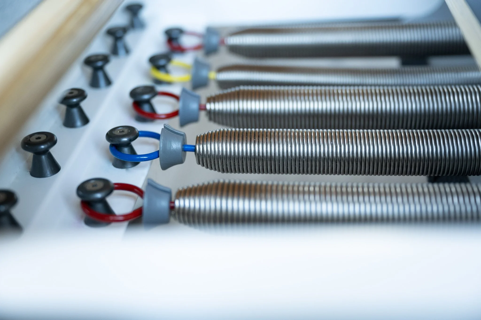 Close-up of metallic coil springs and colorful wires connected to a white surface, likely part of a heating or cooling system.