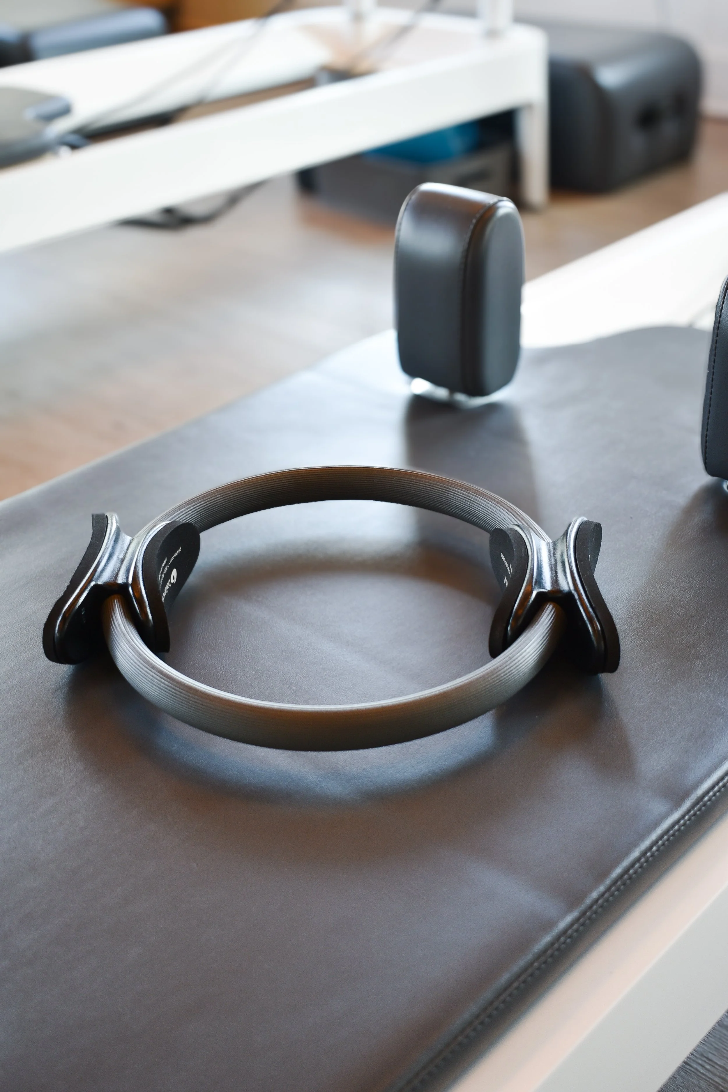 A pair of black and gray headphones resting on a dark surface, with blurred background showing a white table and black objects.
