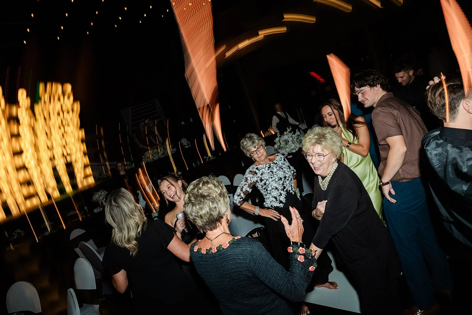 Group of people dancing and socializing at a lively indoor event with bright lights and decorations.