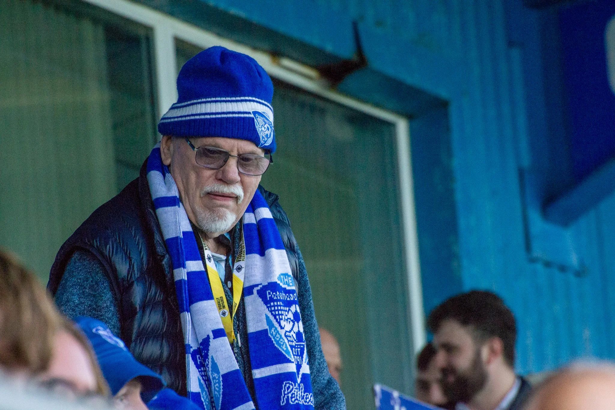 Peterhead FC supporter wearing glasses and a blue-and-white club hat and scarf.