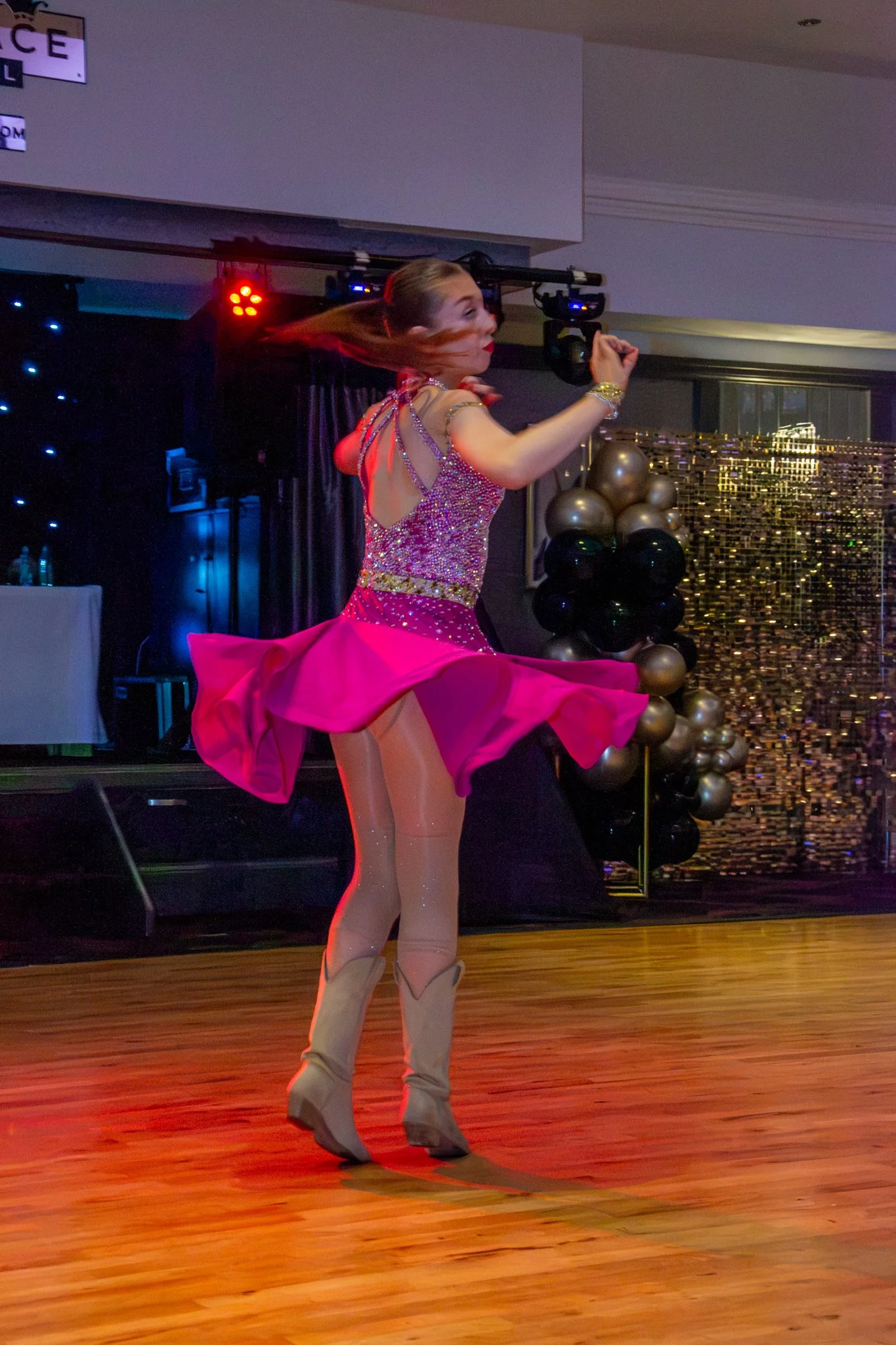 Dancer turning in a bright pink dress, with her skirt flaring out.