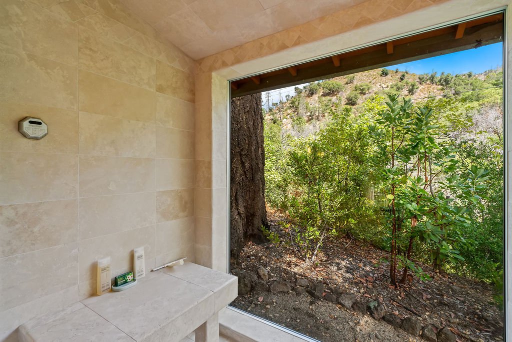 Bathroom with view of trees and hillside through large glass window