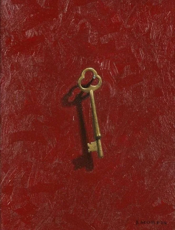 A gold-colored key with a heart-shaped bow lying on a red textured surface.