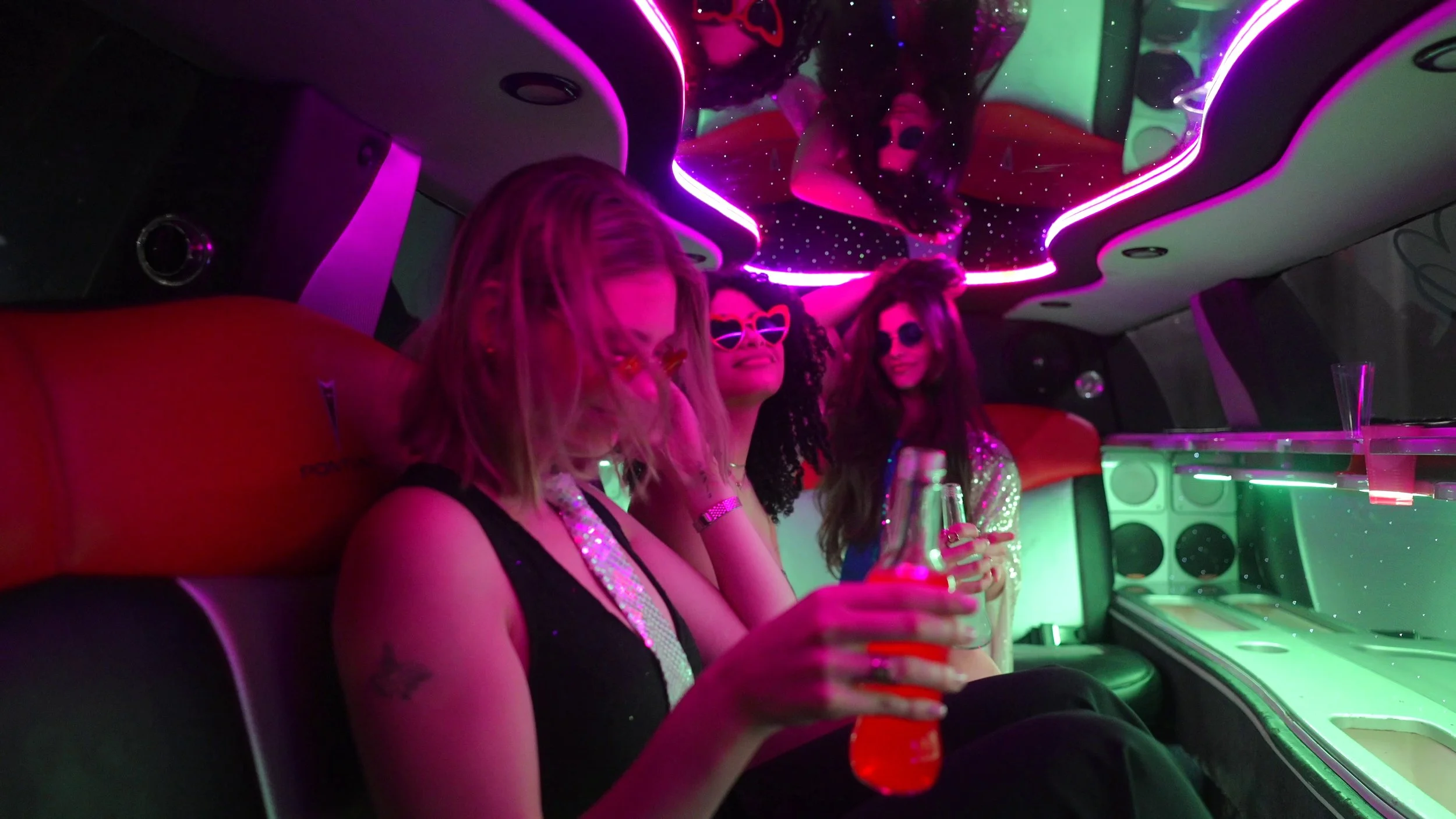three-beautiful-young-women-laughing-and-drinking-together-inside-a-luxury-limousine-w-SBI-358344383.jpg