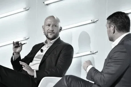Todd Goldstein holding a microphone during a seated discussion.