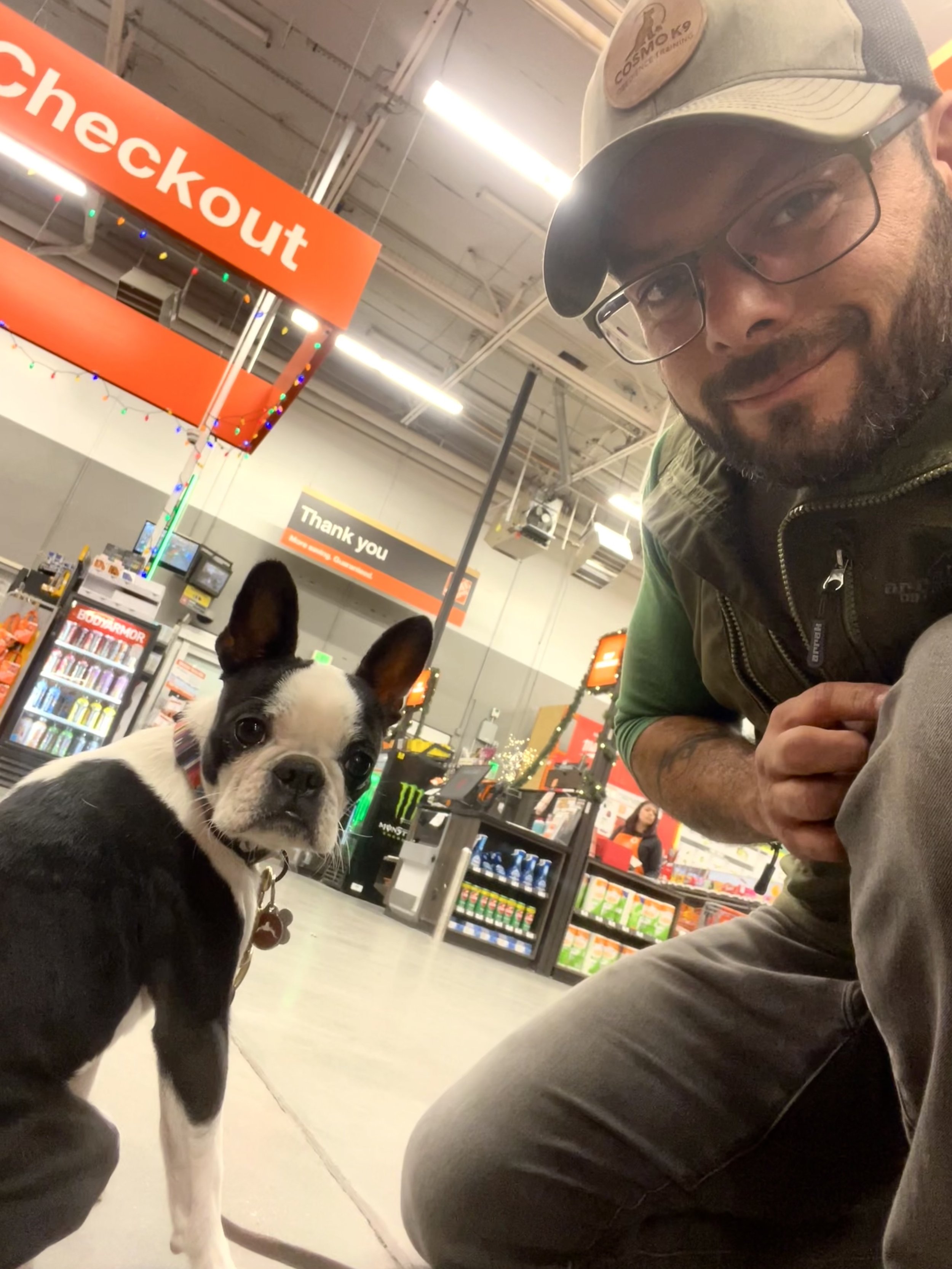 Man kneeling by small dog in Home Depot and taking a selfie.