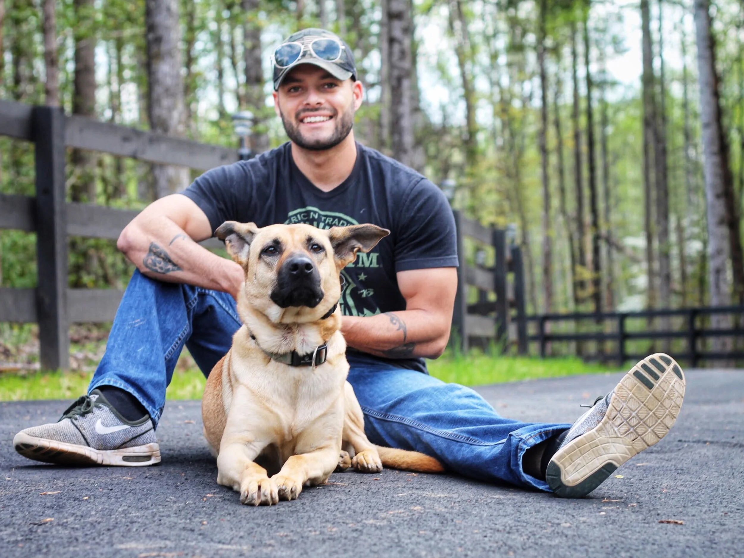 CEO of Cosmo K9 Obedience Chris Ramirez sitting on the ground with his service dog Korra