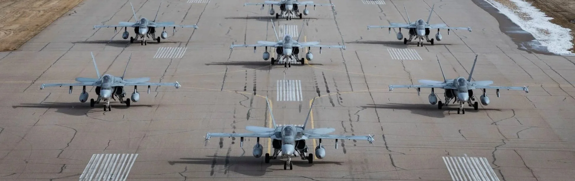 Six fighter jets parked on an airstrip arranged in two rows facing forward.